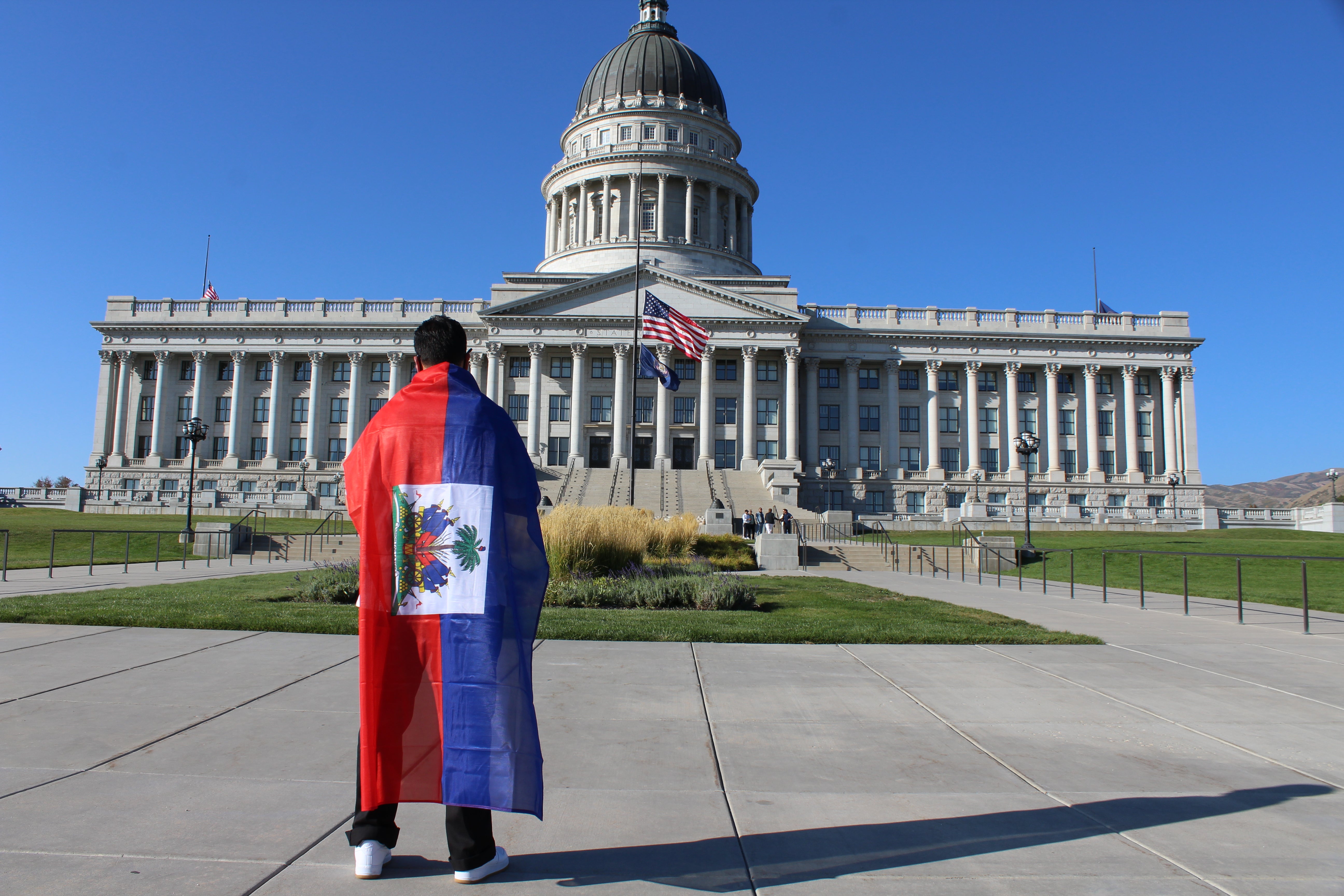 A supporter of Haitian immigrant rights draped in the Caribbean country’s flag stands in front of the Utah Capitol on Friday, Sept. 24.