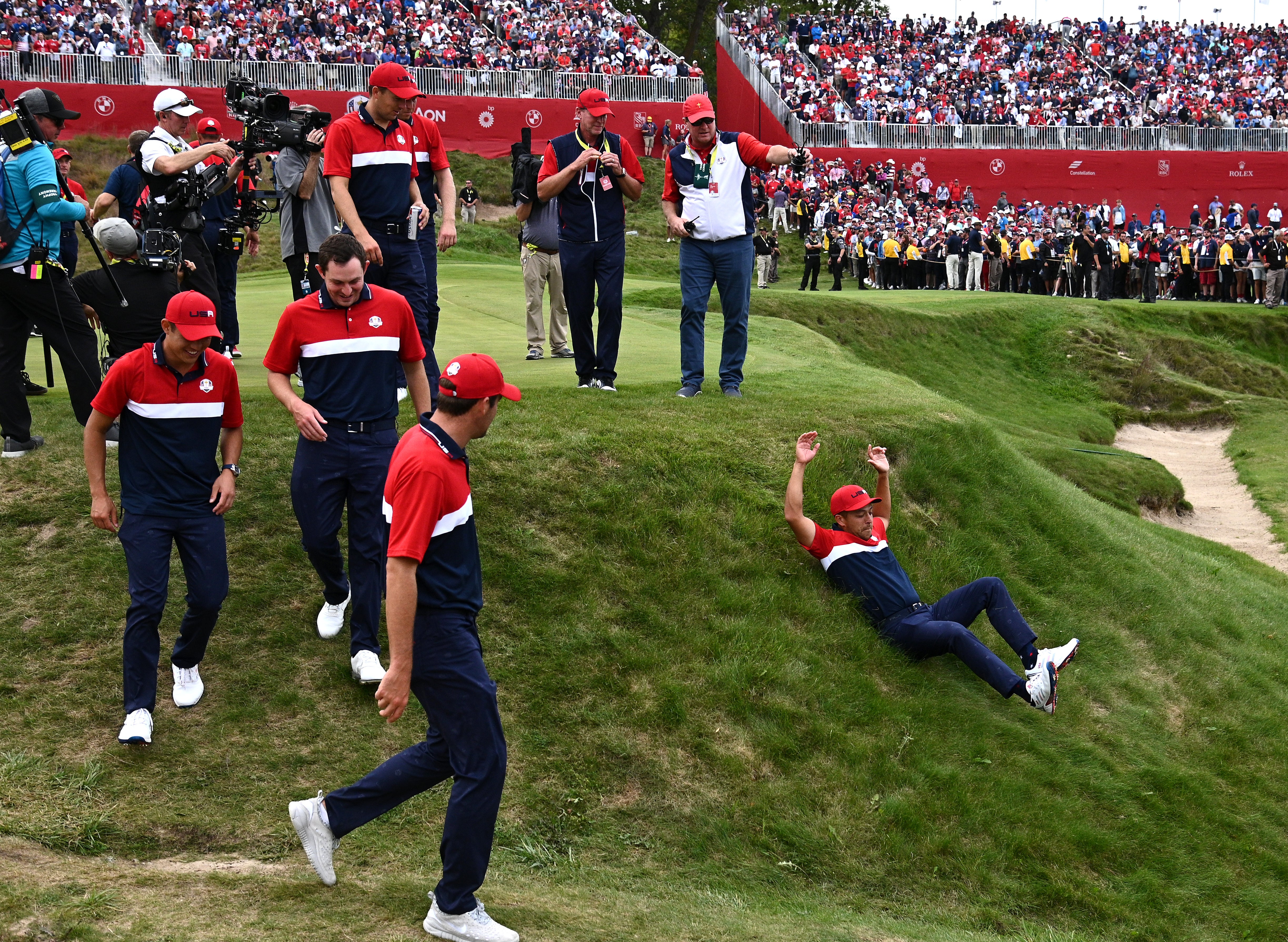 A jubilant Xander Schauffele slides down an embankment hill on his way to the podium after Team USA’s Ryder Cup win (Anthony Behar/PA)