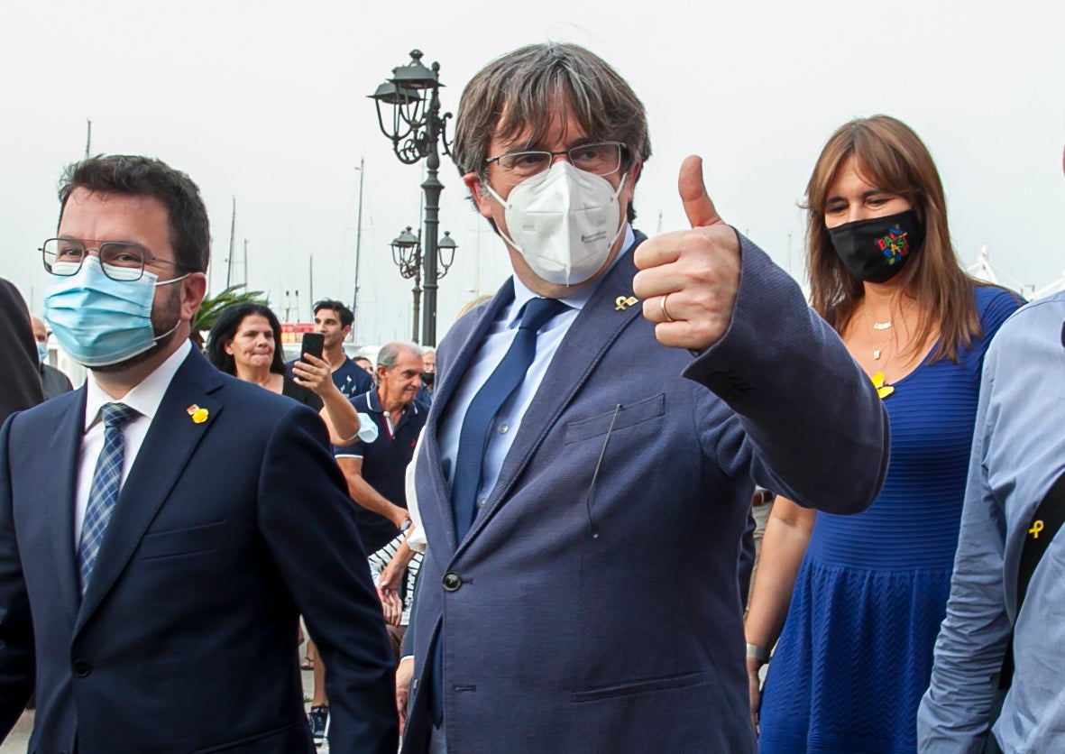 Catalan separatist leader Carles Puigdemont, center, gives thumbs up as he walks with Catalonia's president Pere Aragones, left, and the Speaker of the Catalan Parliament Laura Borras, right in Alghero, Sardinia