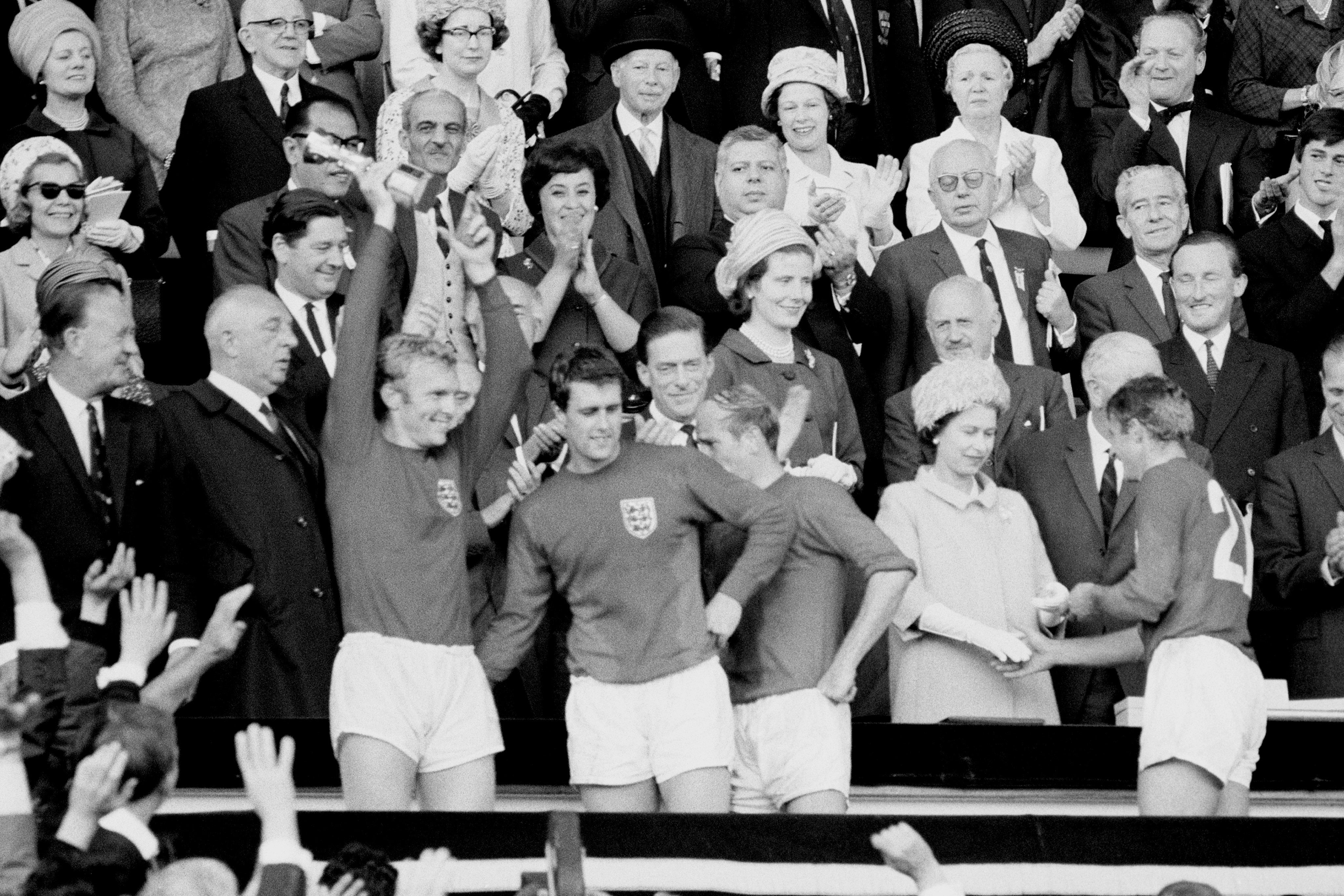 Hunt receives his medal from the Queen while captain Bobby Moore celebrates with the trophy after the 1966 final (PA Archive)