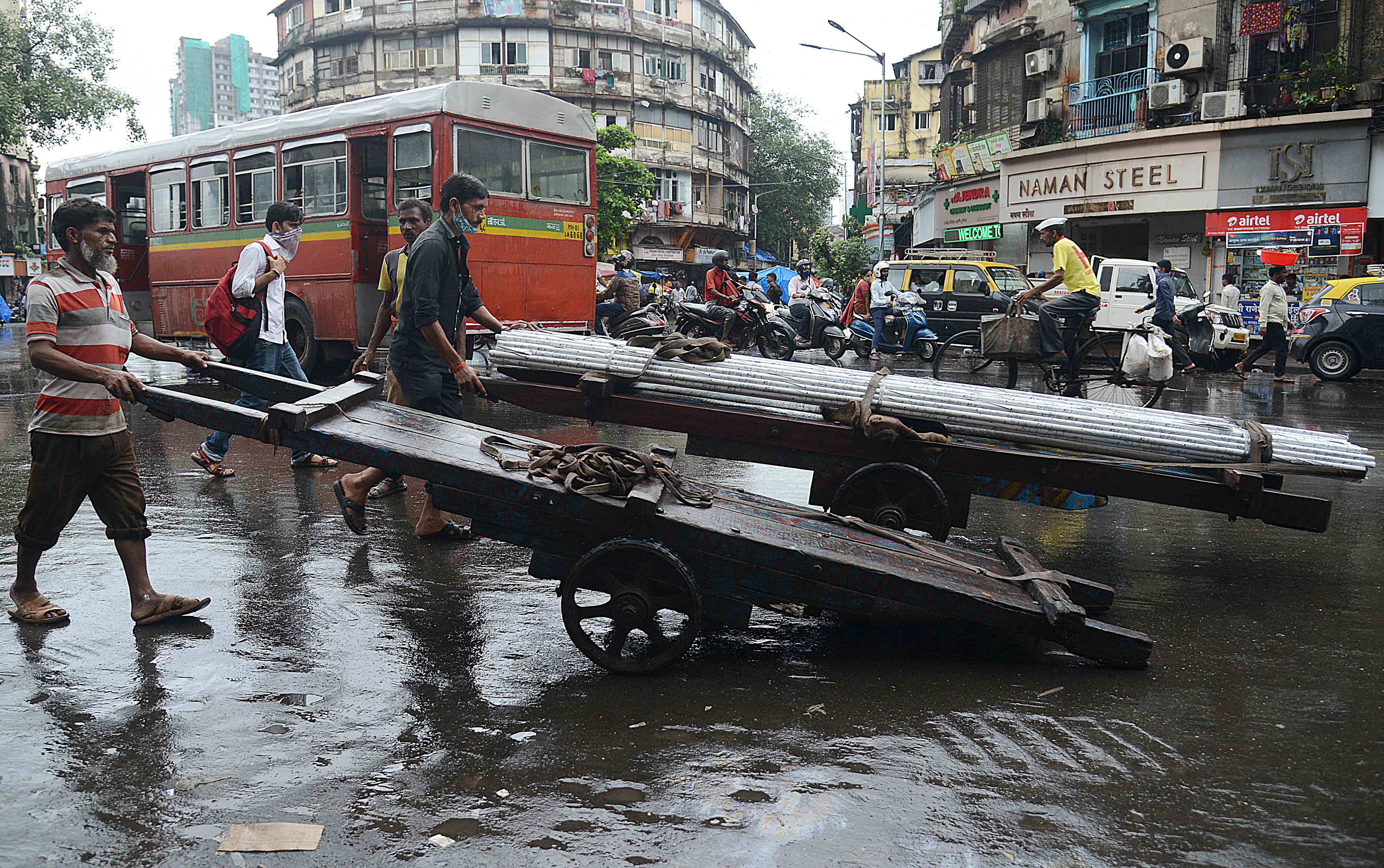 Men push handcarts along a street in Mumbai