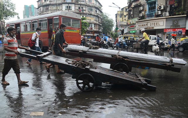 <p>Men push handcarts along a street in Mumbai</p>