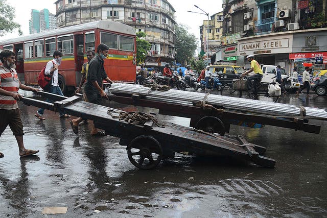 <p>Men push handcarts along a street in Mumbai</p>