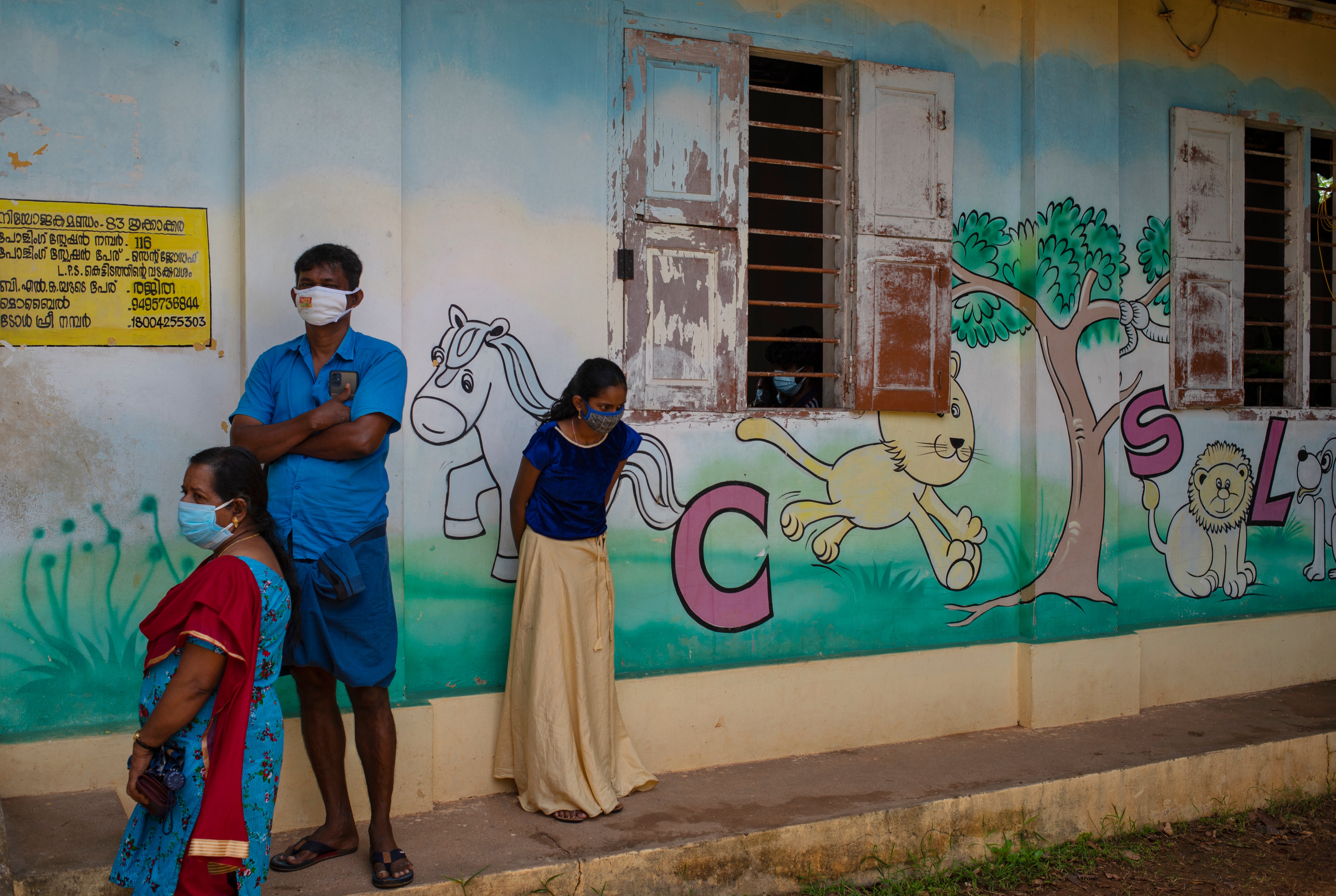 People wearing masks wait to get vaccinated for Covid-19 outside a school in Kochi, Kerala state