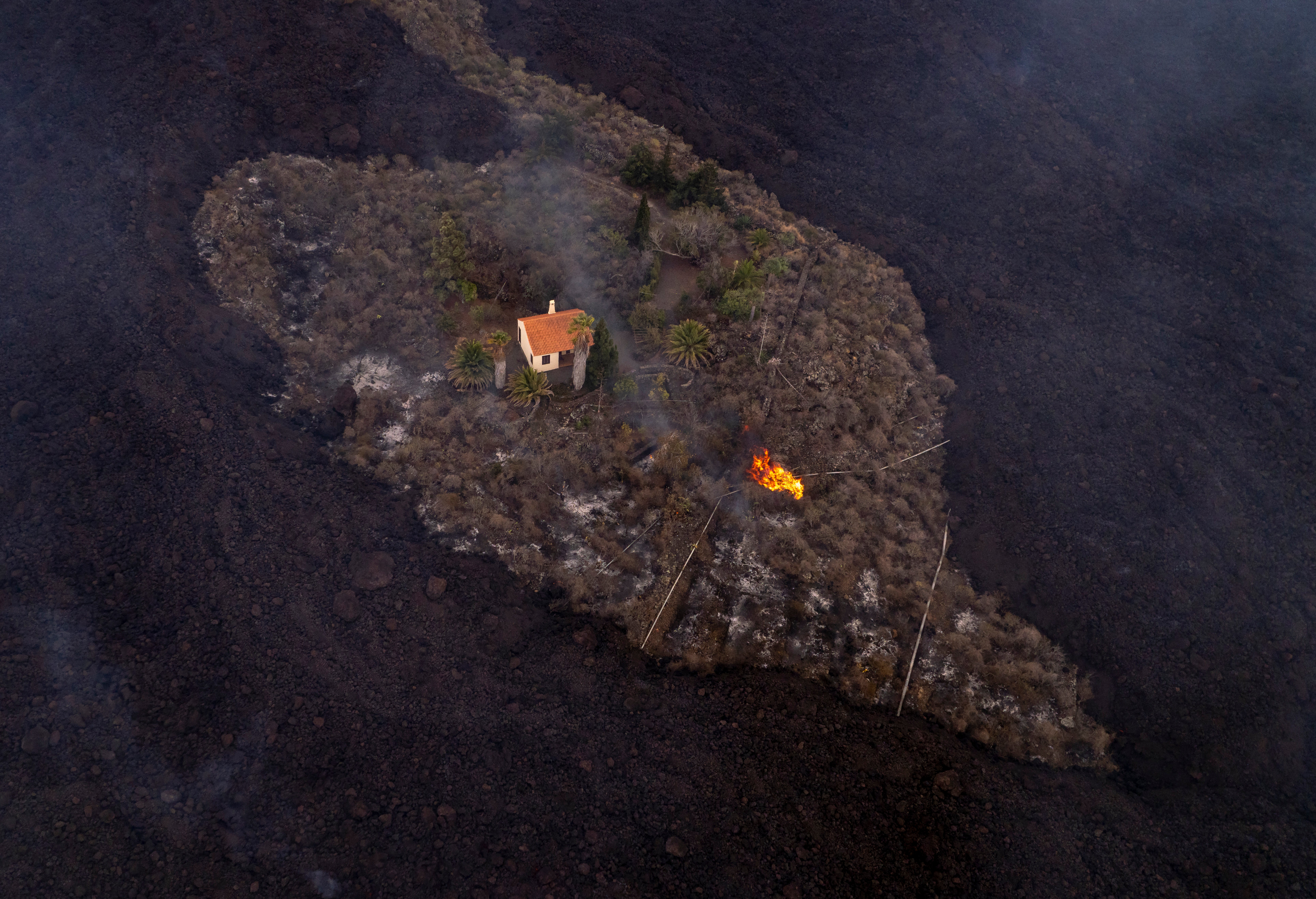 In this photo, provided by iLoveTheWorld, a house remains intact as lava flows around it following a volcanic eruption