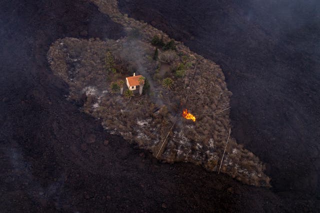 <p>In this photo, provided by iLoveTheWorld, a house remains intact as lava flows around it following a volcanic eruption</p>