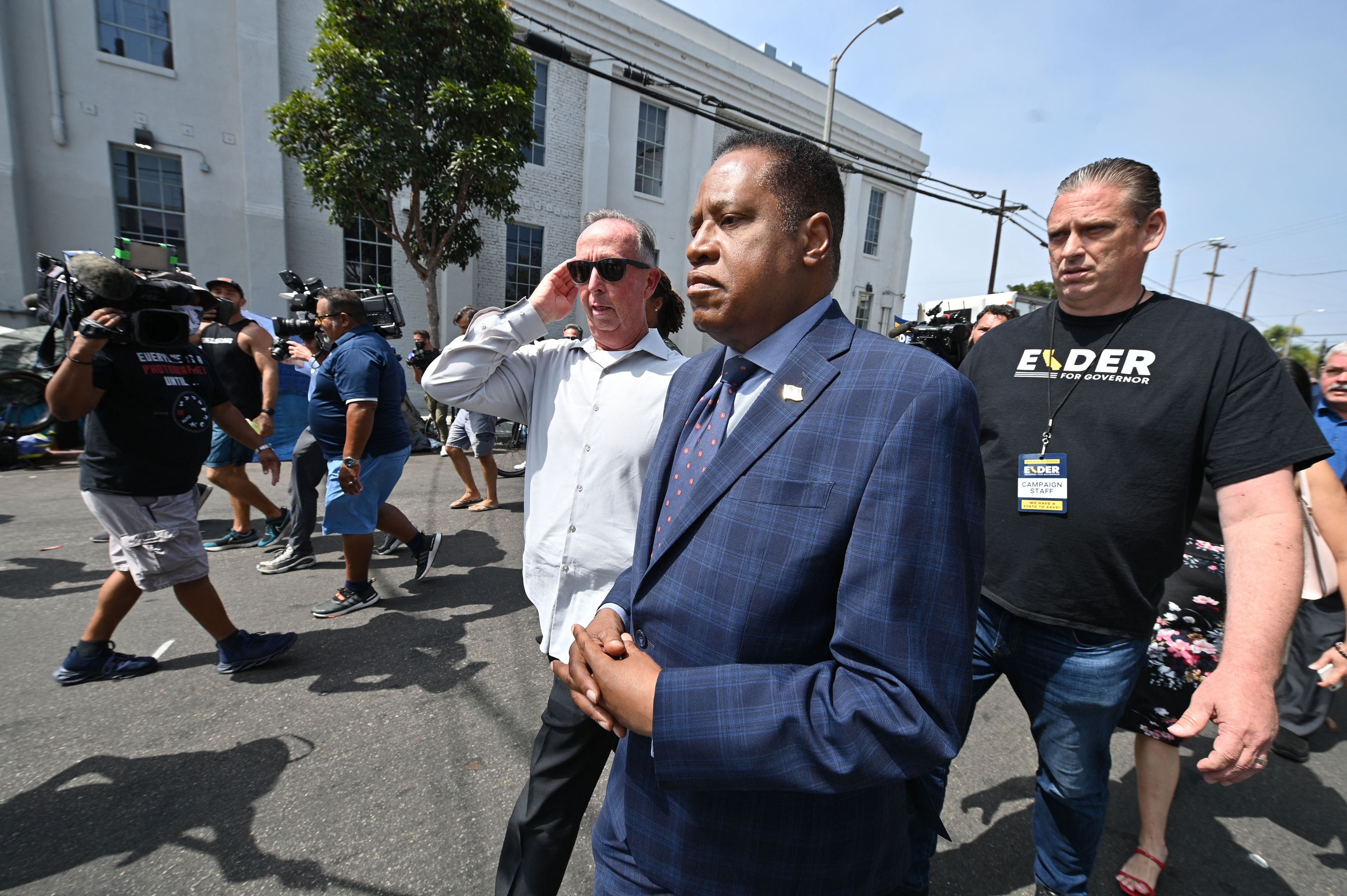 Conservative talk show host and gubernatorial recall candidate Larry Elder (C) walks along streets lined with tents of unhoused people, in the Venice neighborhood of Los Angeles, California, 8 September 2021.