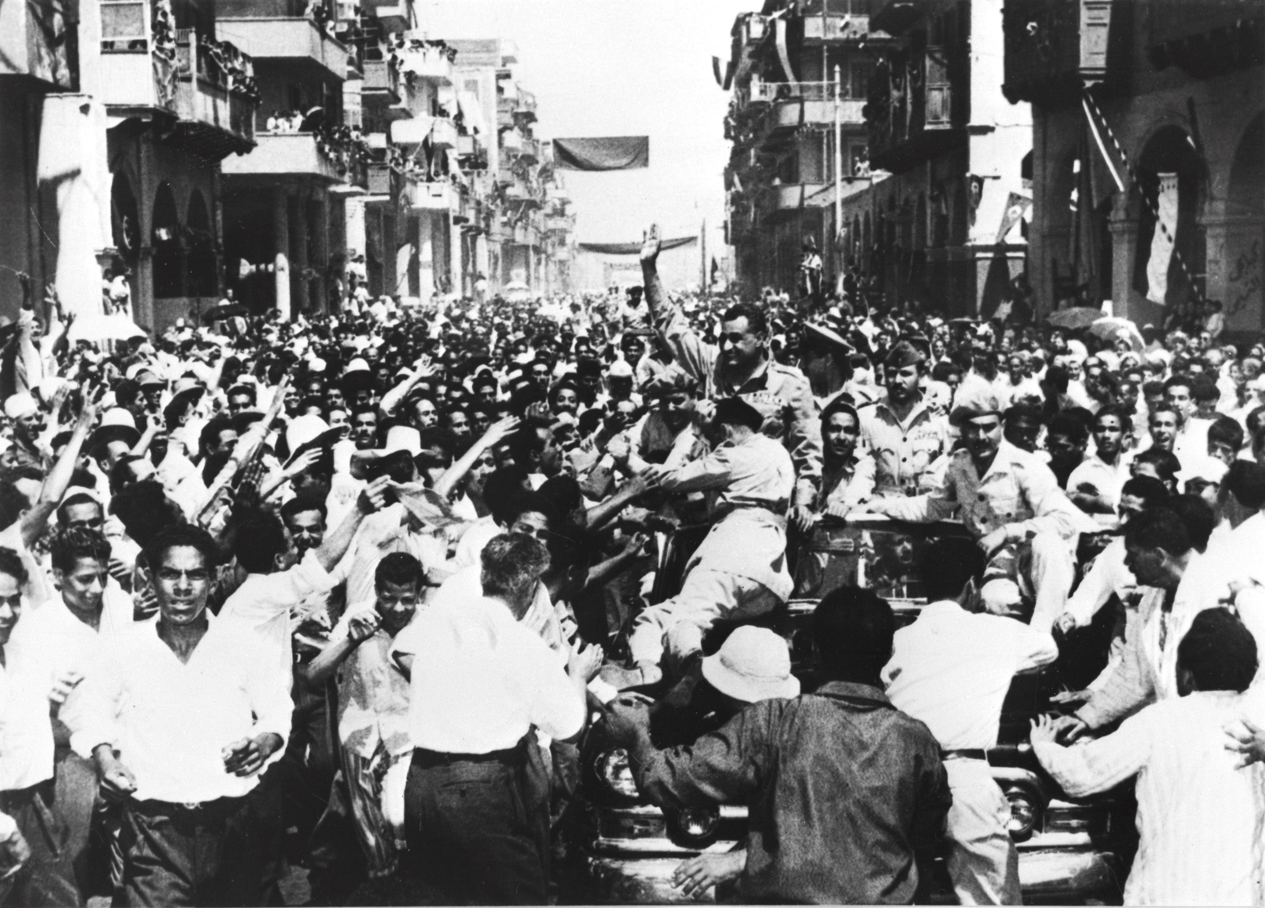 Colonel Nasser waves to the crowd that descended to cheer him on the streets of Port Said after the evacuation of British forces from Egypt on 22 June 1956