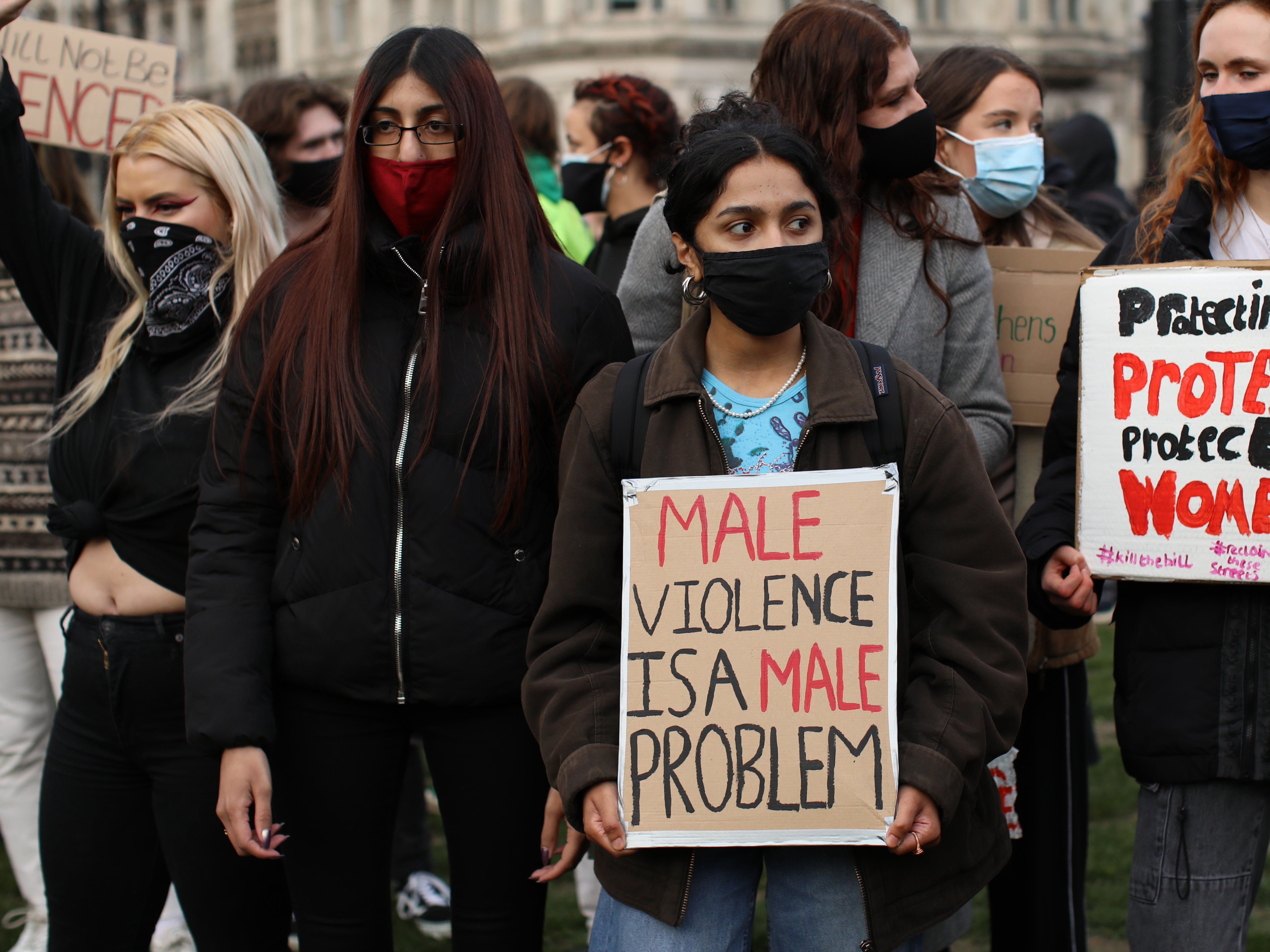 A woman holds a sign reading ‘male violence is a male problem'