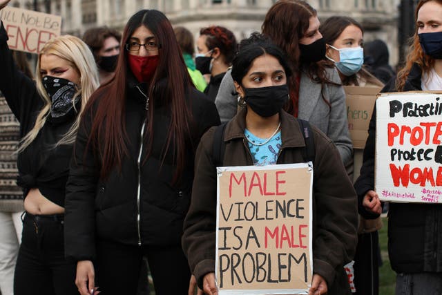 <p>A woman holds a sign reading ‘male violence is a male problem'</p>