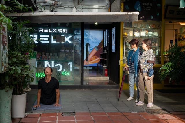 <p>Representational: Two women watch a man doing yoga in an alley on 11 September 2021 in Shanghai, China</p>