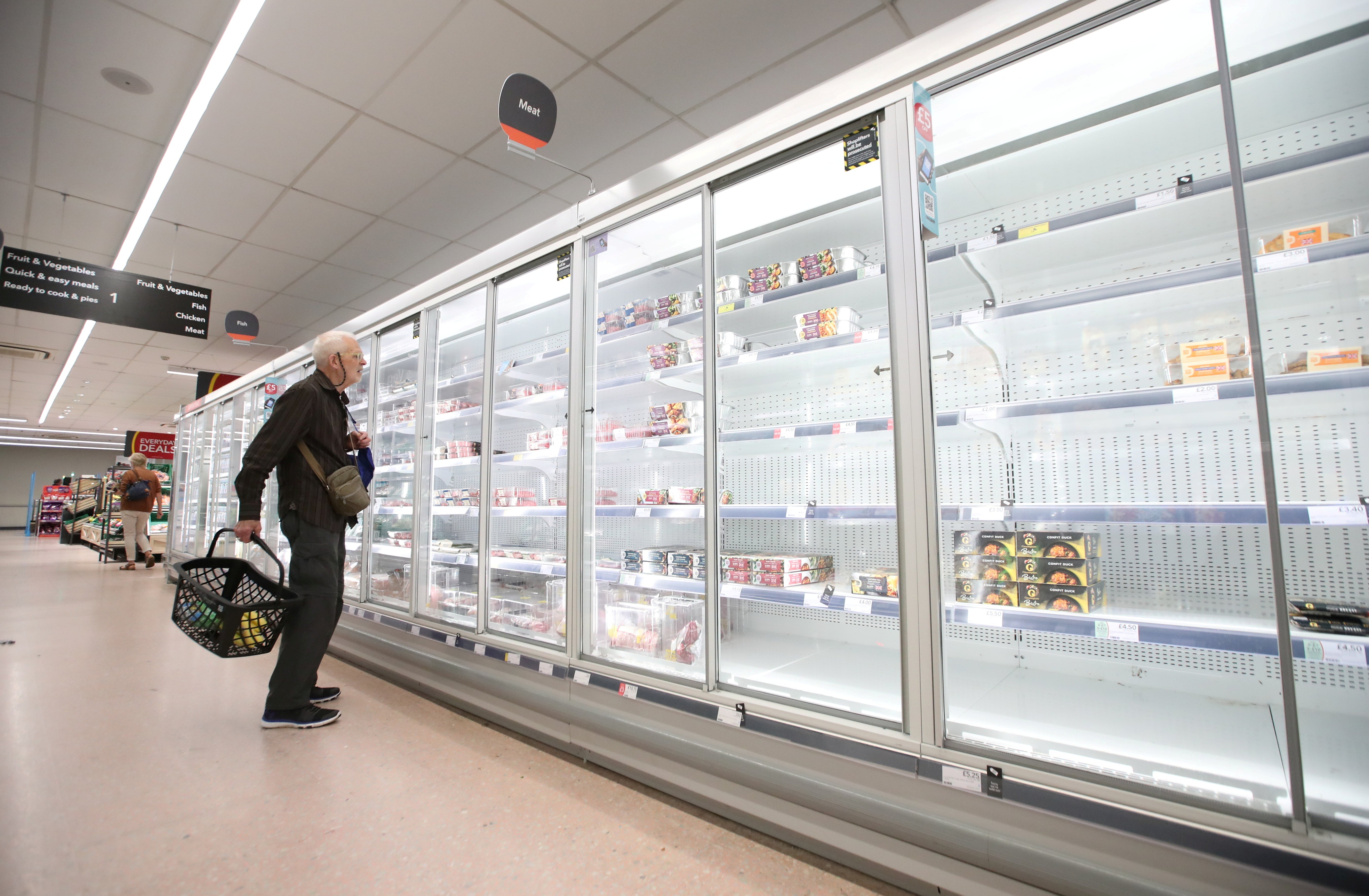 A shopper looks at the empty shelves in Co-Op supermarket, Harpenden