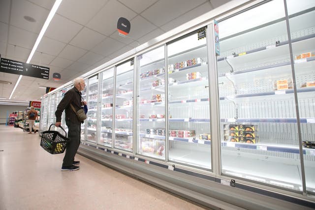 <p>A shopper looks at the empty shelves in Co-Op supermarket, Harpenden</p>