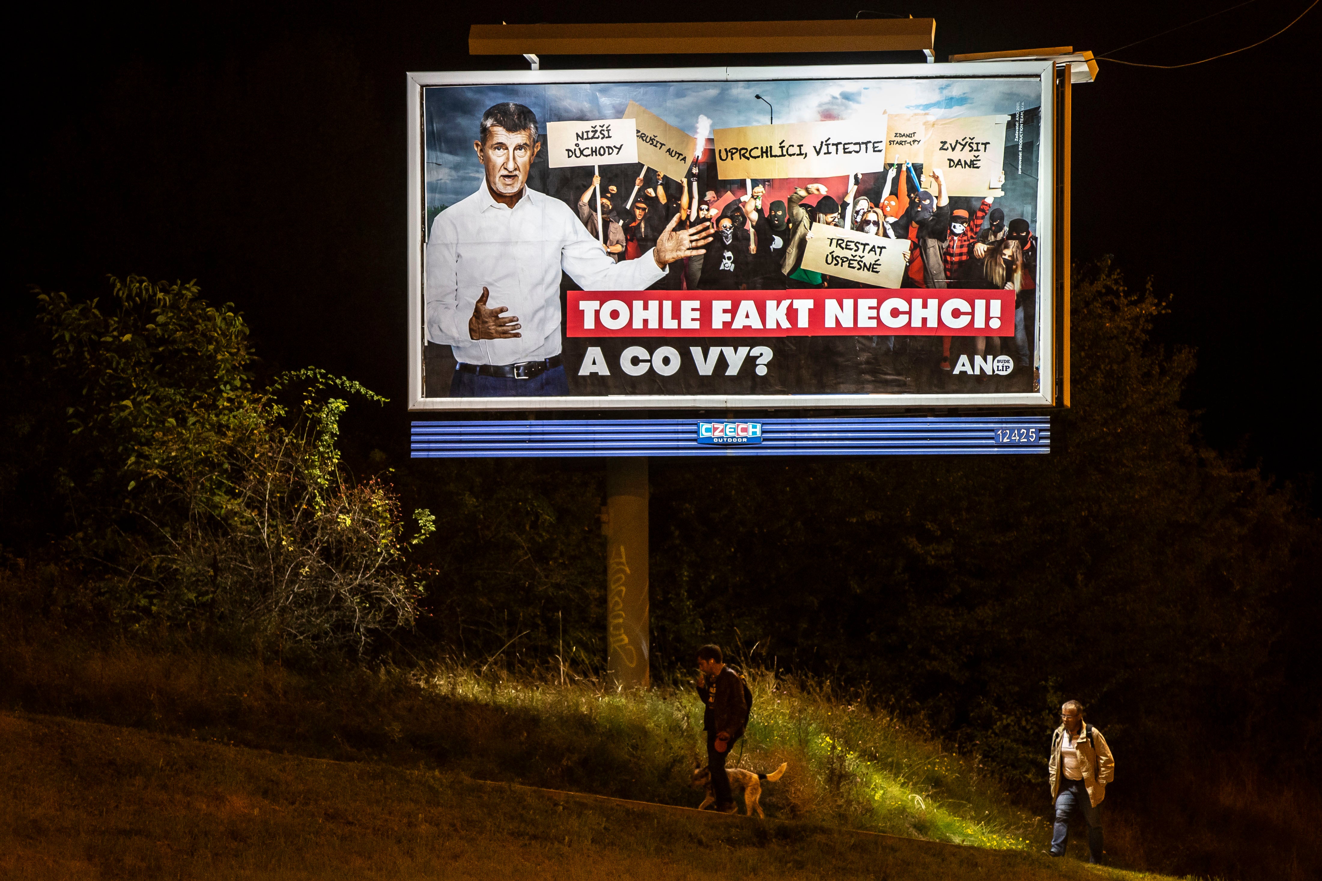 People walk past an election campaign poster for Andrej Babis of the ANO party in Prague