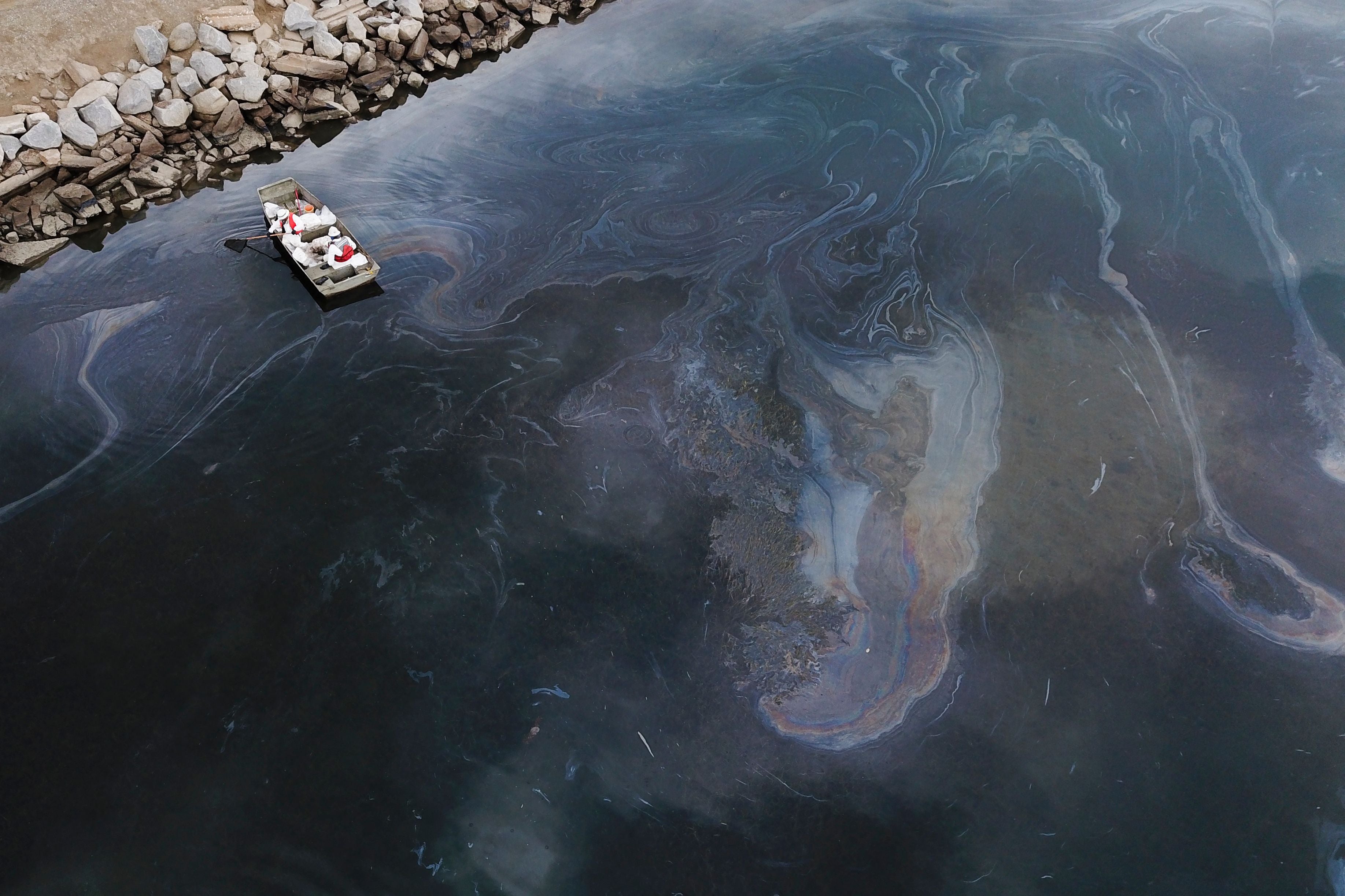 This aerial picture taken on October 4, 2021 shows environmental response crews cleaning up oil that flowed near the Talbert marsh and Santa Ana River mouth, creating a sheen on the water after an oil spill in the Pacific Ocean in Huntington Beach, California.