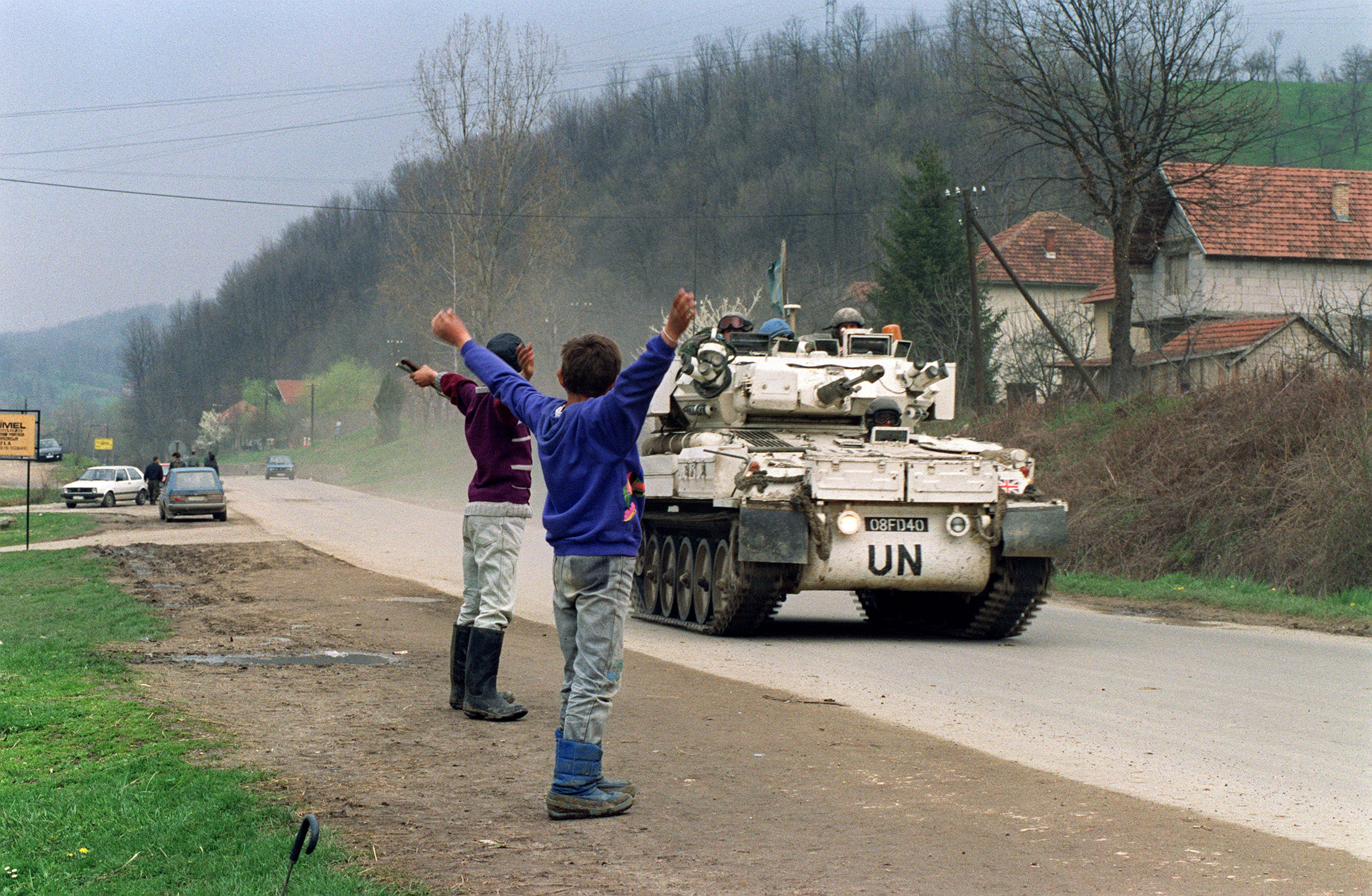 Two Bosnian boys salute a Canadian blue helmets convoy near Tuzla in April 1993