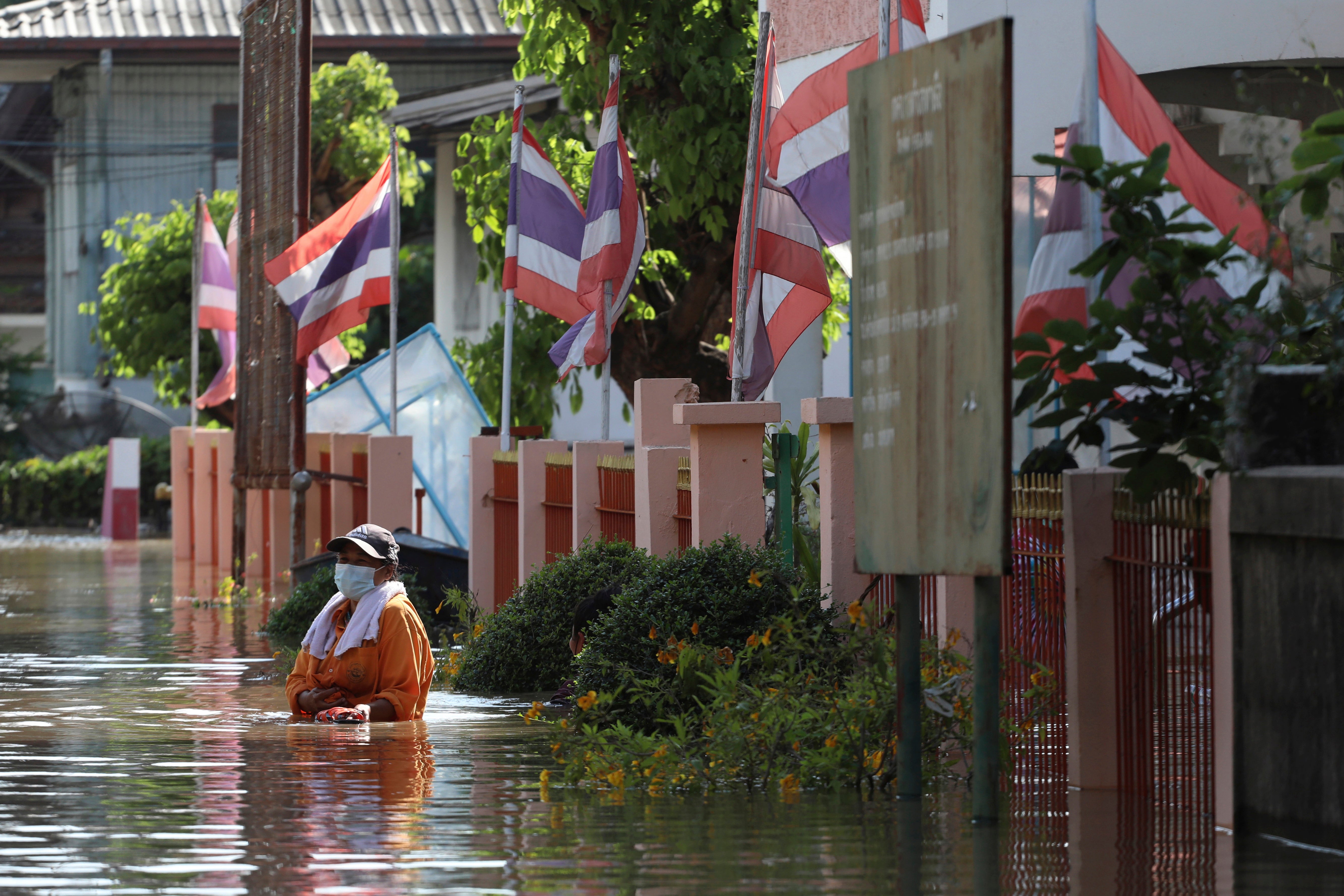 A woman wades through floodwaters in Ayutthaya province, north of Bangkok, Thailand, Monday, October 4, 2021.