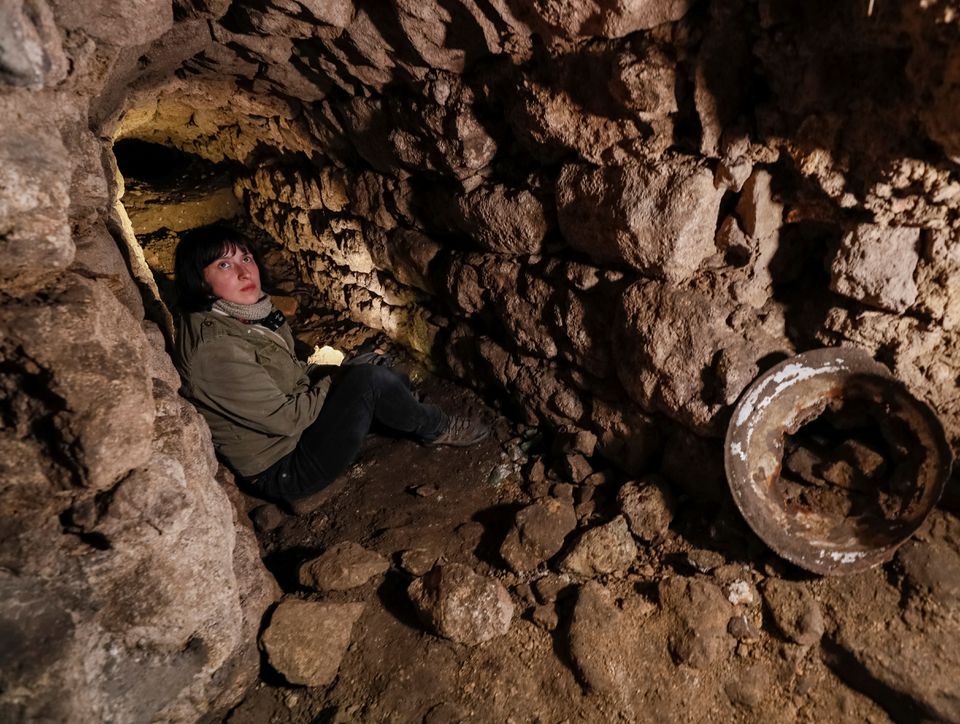 Historian Hanna Tychka explores a cave at the city sewage system where dozens of Jews were hiding from the Nazis during World War Two in Lviv, Ukraine Garanich
