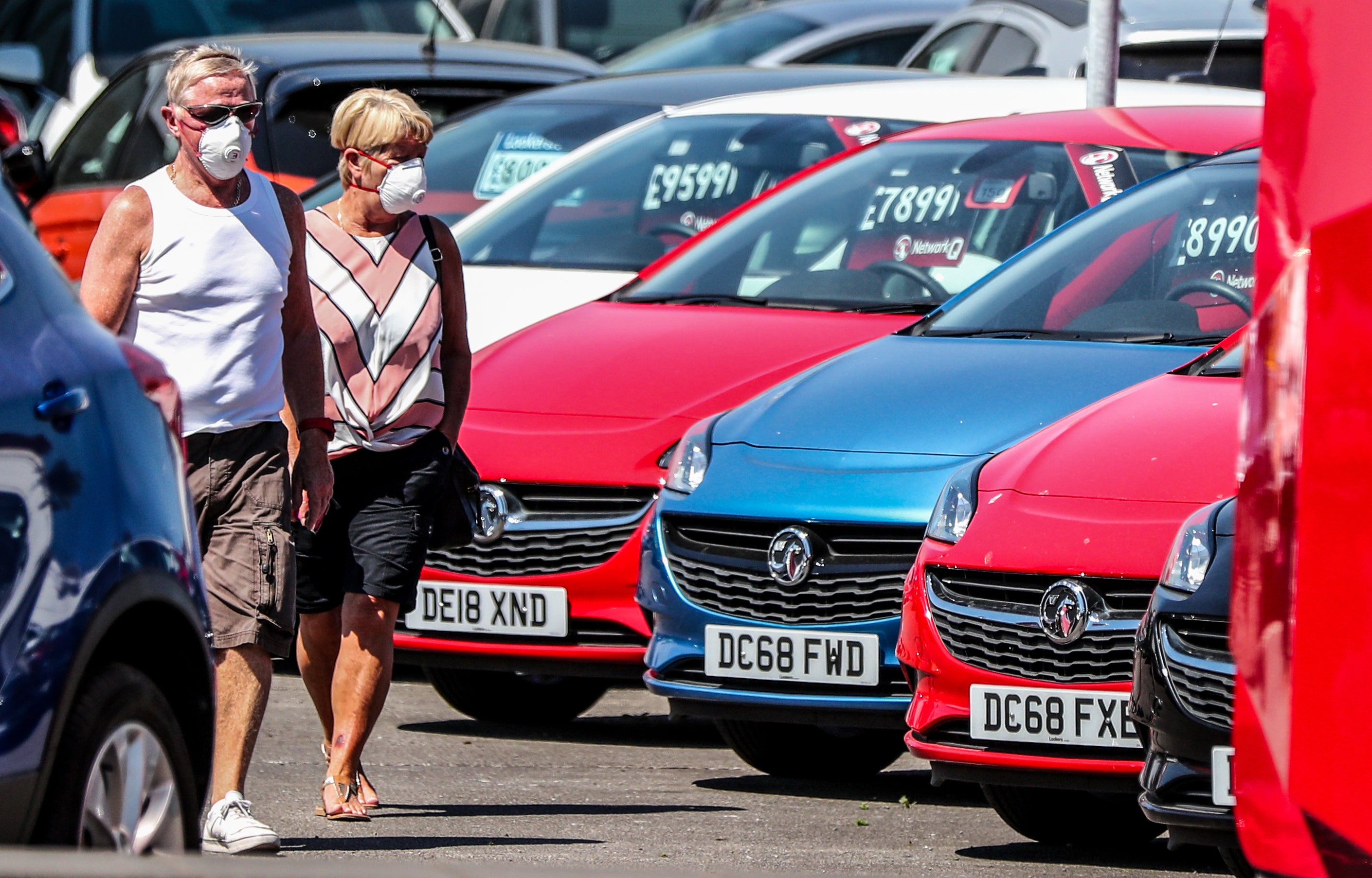 A couple walk past cars on the forecourt of Vauxhall Lookers in Speke, Liverpool (Peter Byrne/PA)