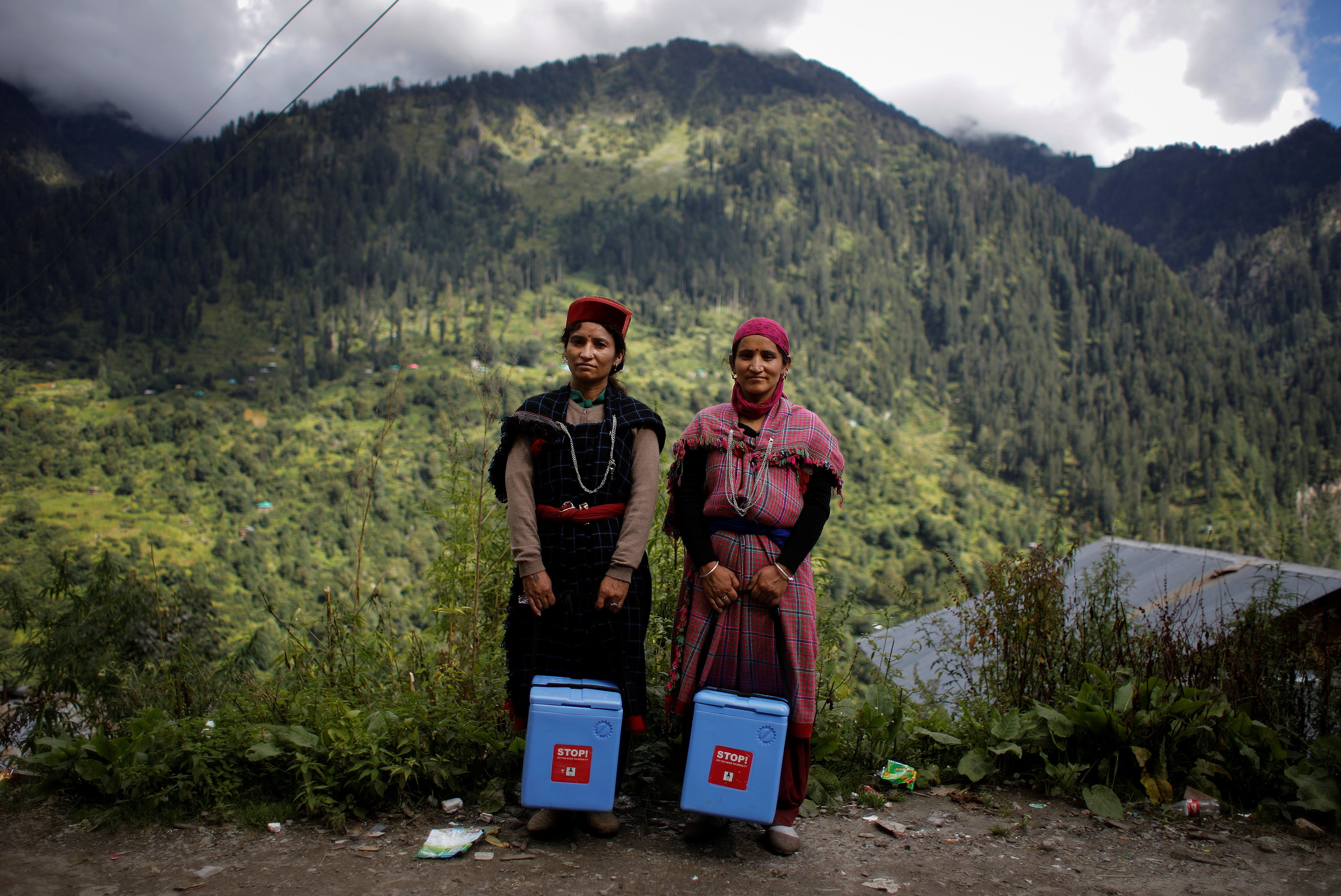 Health workers Nirma and Phula Devi hold boxes containing Covishield vaccines intended for Malana villagers in the Himalayan state of Himachal Pradesh