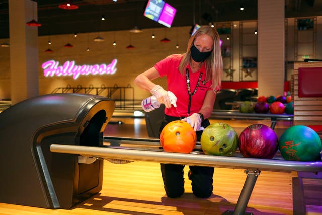 A member of staff at a Hollywood Bowl in Essex cleans the bowling balls (Steve Parsons/PA)