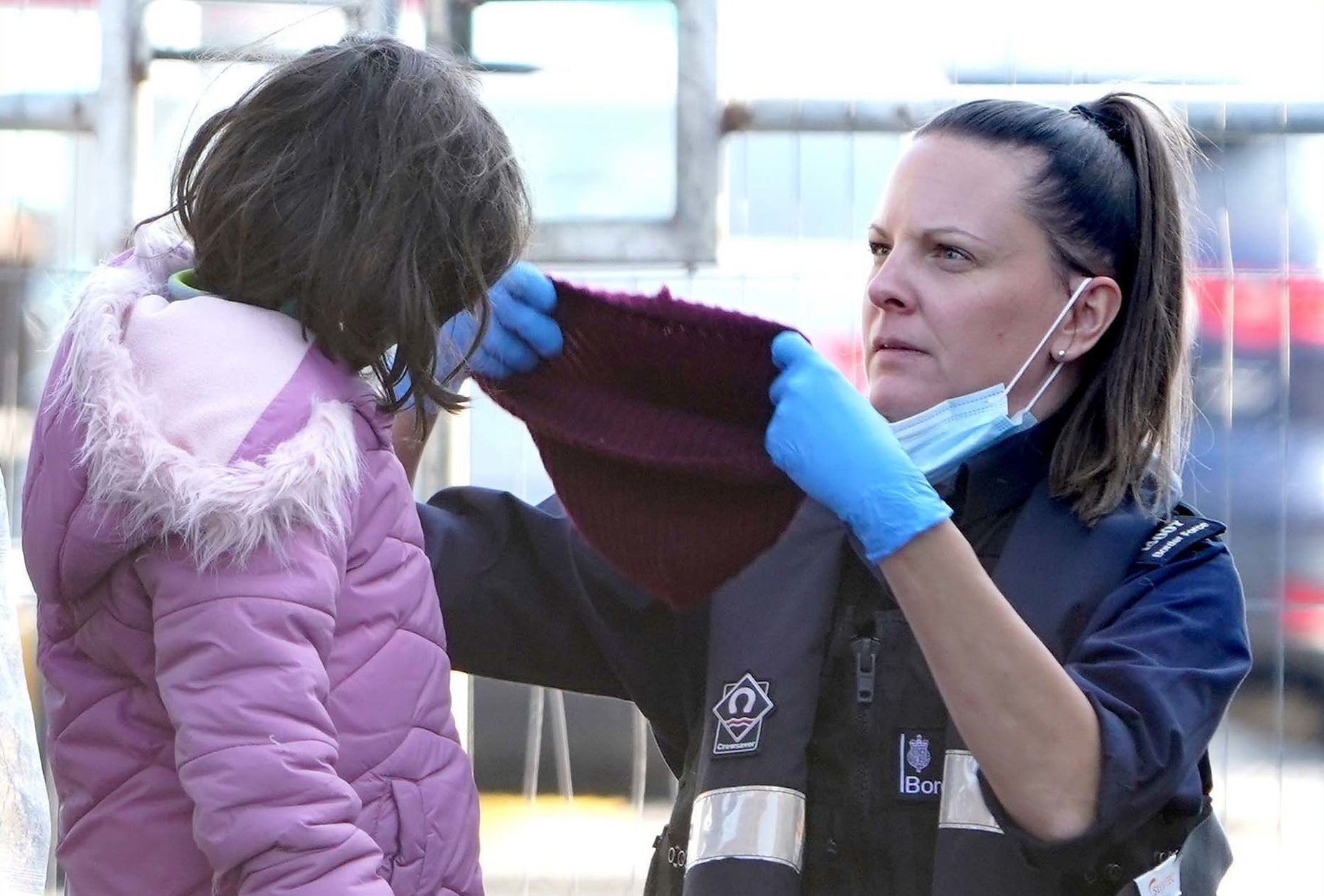 Border Force officer puts a hat on a girl who arrived in Kent with other migrants on a small boat