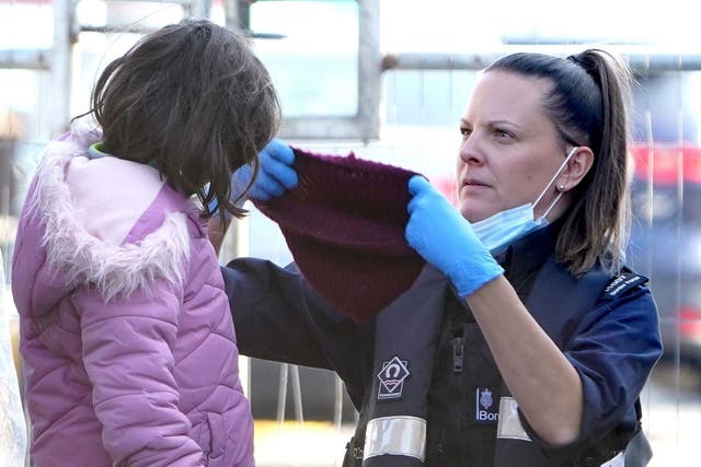 <p>Border Force officer puts a hat on a girl who arrived in Kent with other migrants on a small boat</p>
