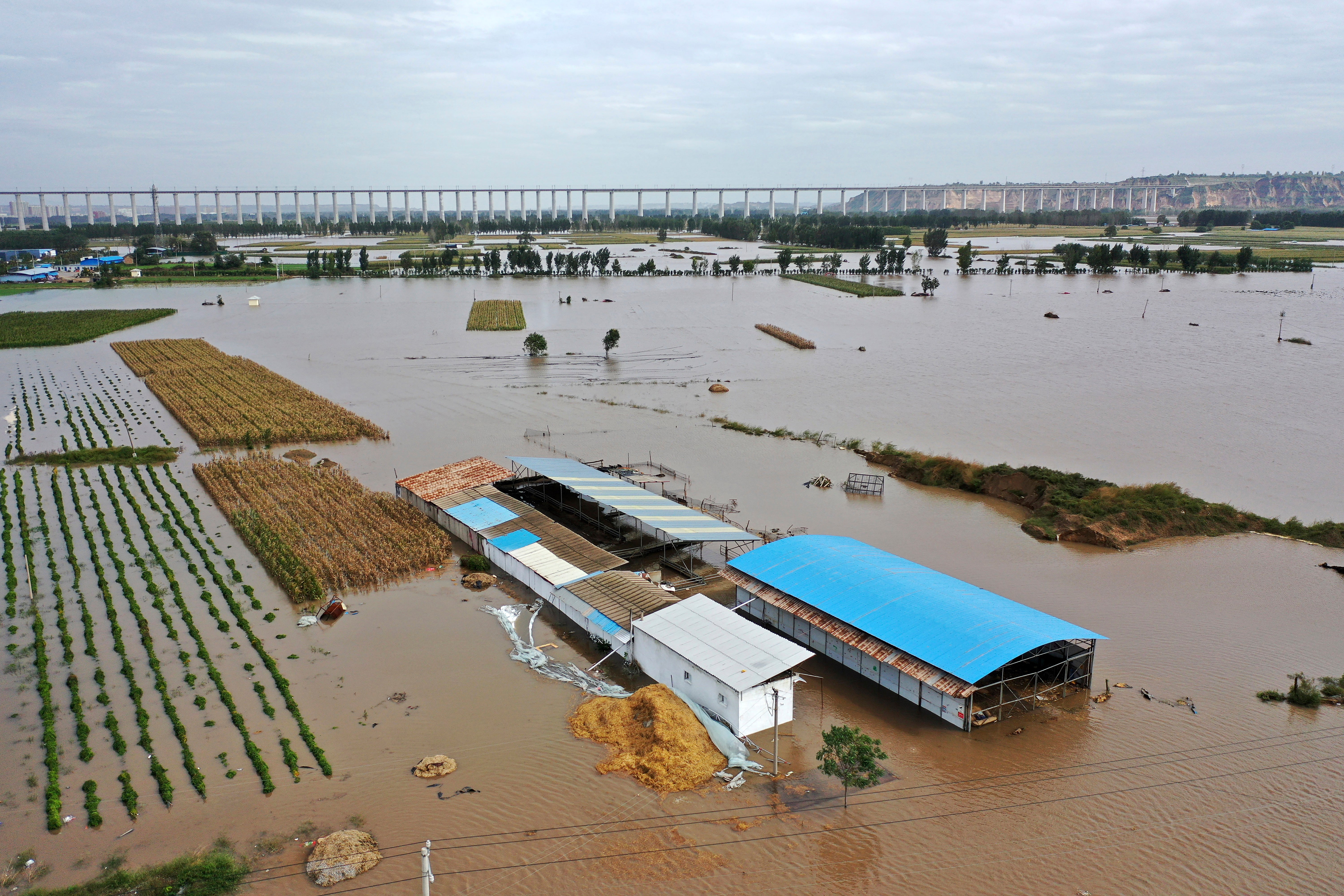 In this photo released by Xinhua News Agency, an aerial photo shows an overflowing river in Shanxi province’s Hejin city