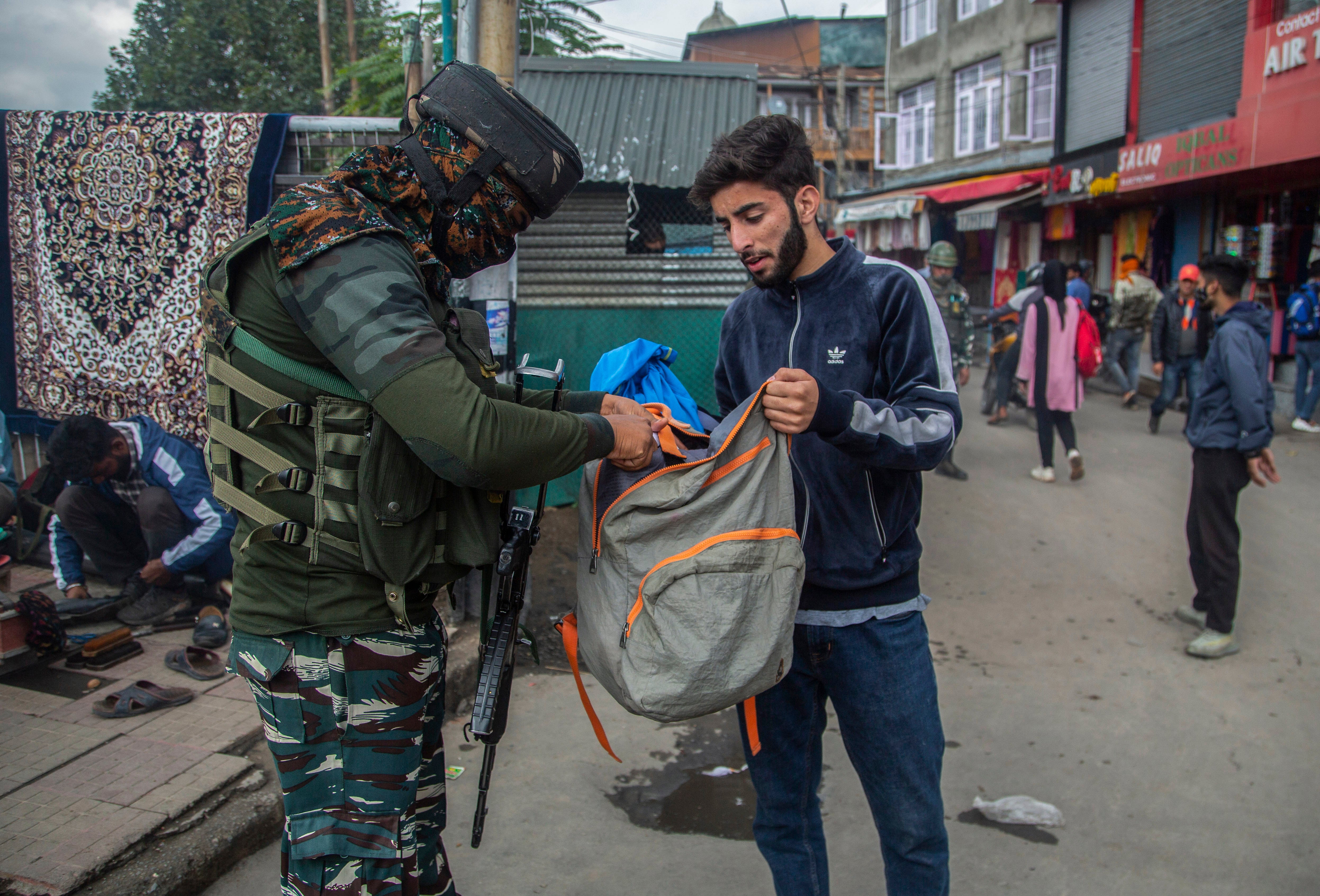 Indian paramilitary soldier checks the bag of a Kashmiri man at a market in Indian administered Kashmir