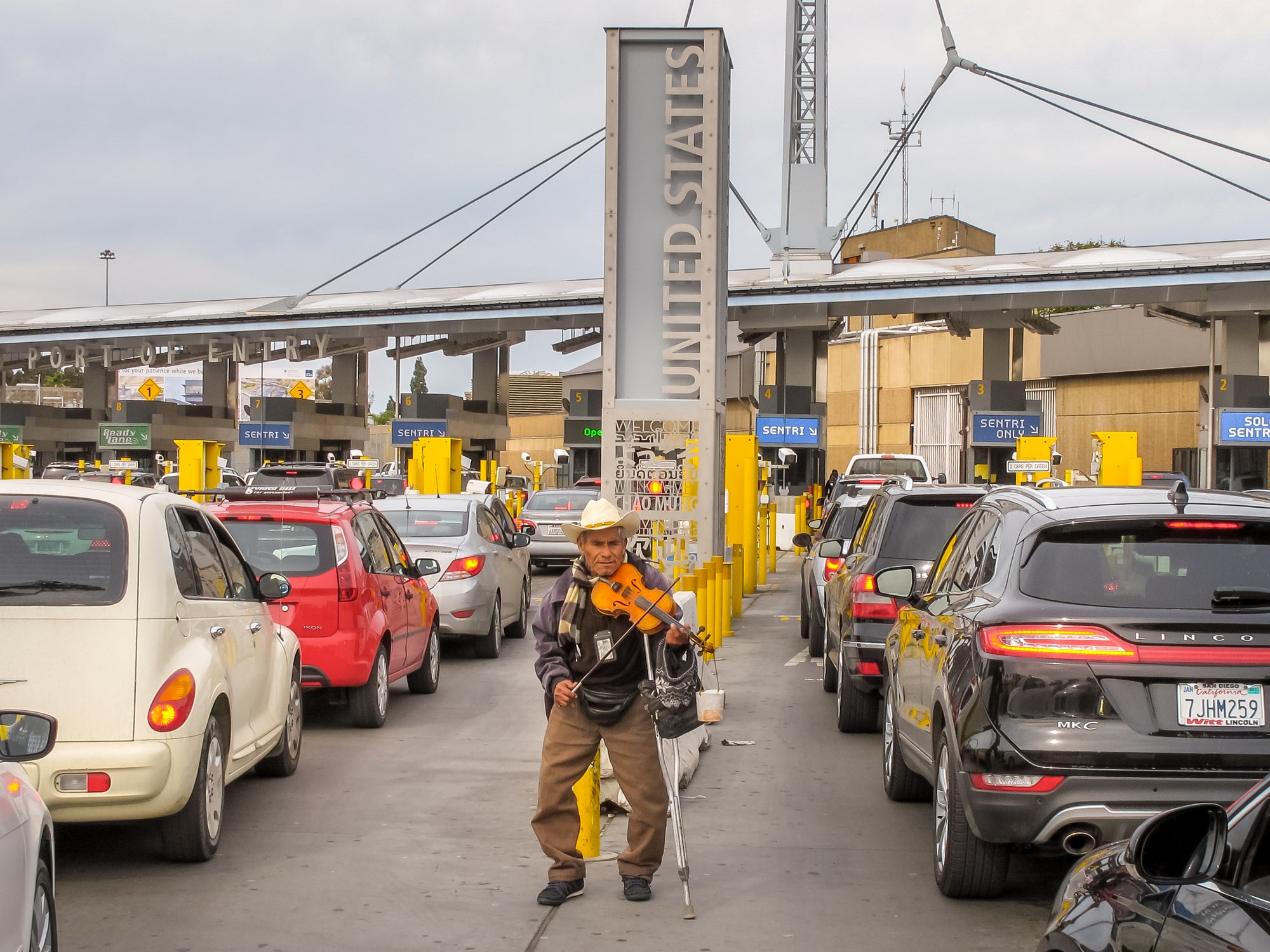 An elderly person plays his violin among the dozens of cars queued on the Mexican side waiting to cross the border between Mexico and the United States, at the border station between Tijuana and San Ysidro.