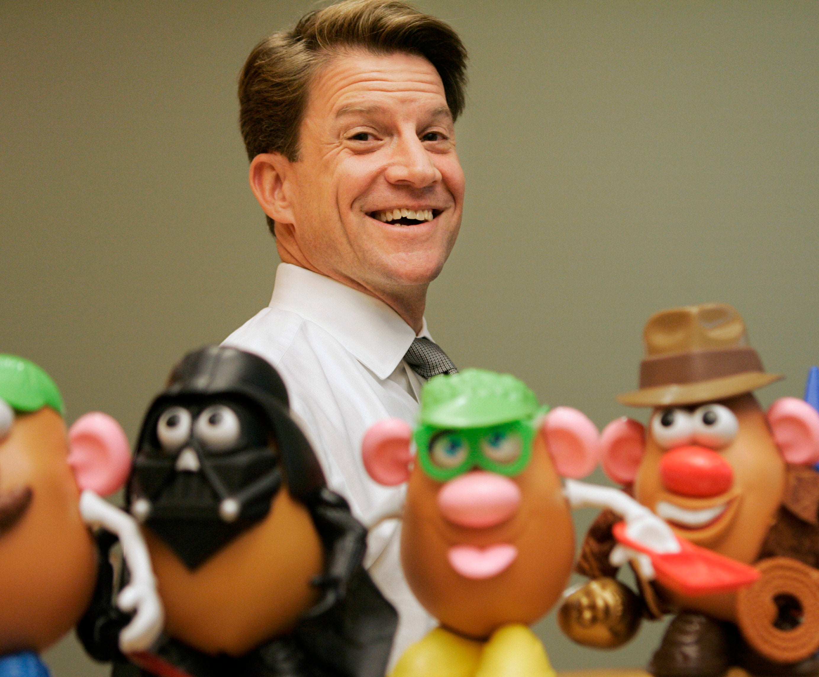 In this 2008 file photo, Brian Goldner stands next to some toy figures at Hasbro’s headquarters, in Pawtucket, Rhode Island