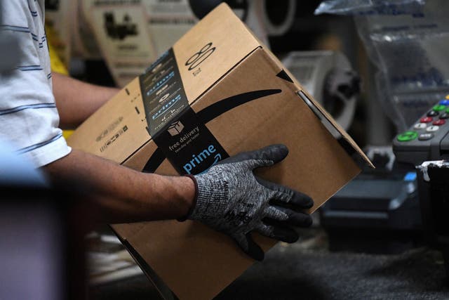 Trabajador ensambla una caja para su entrega en un almacén de Amazon