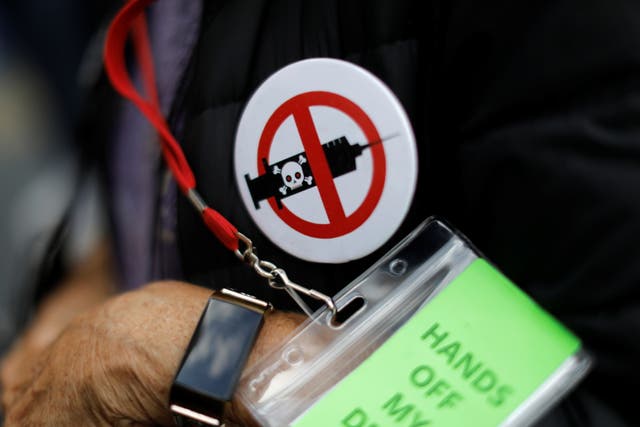 <p>A man wears an anti-vaccine button as people and teachers protest against New York City mandated vaccines against the coronavirus disease (COVID-19) in front of the United States Court in Manhattan in New York City, New York, U.S.</p>