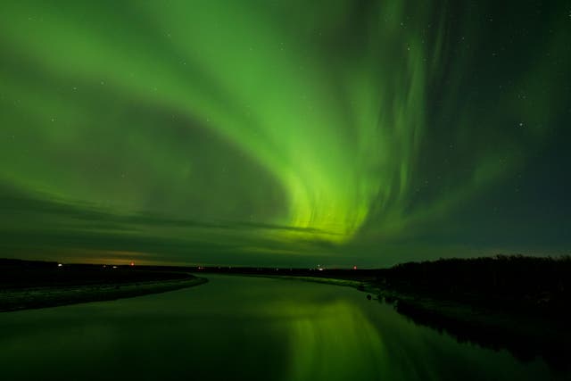 <p>The aurora borealis, or northern lights, fill the early morning sky above the Kenai River near its mouth in Kenai, Alaska.</p>