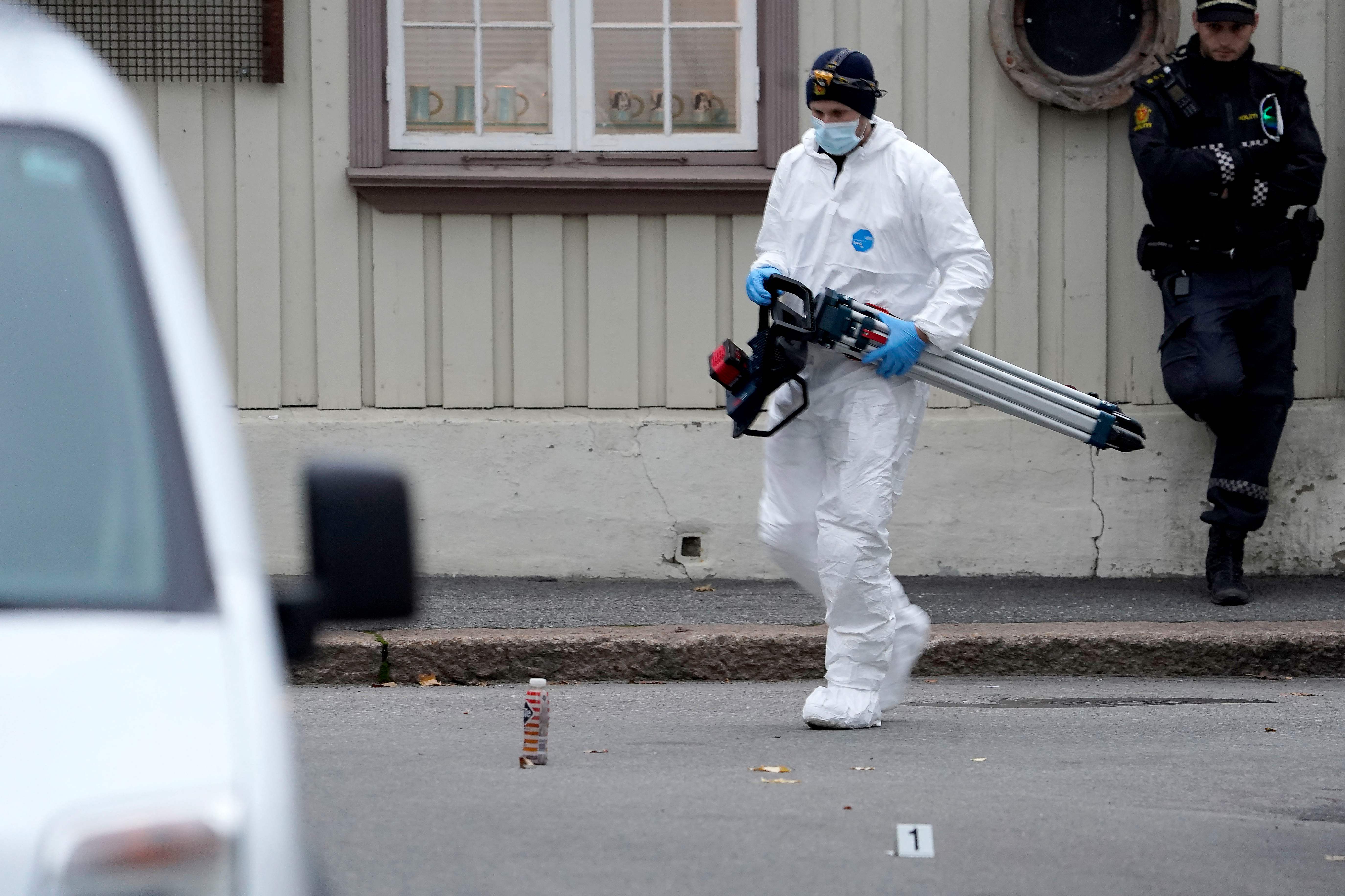 A police forensic officer carries material during investigations after the shootings