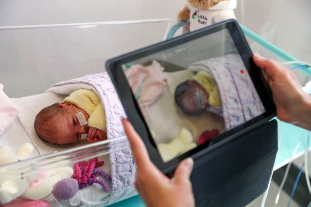 <p>A nurse makes a video of a newborn baby in the maternity ward at Frimley Park Hospital in Surrey in May </p>