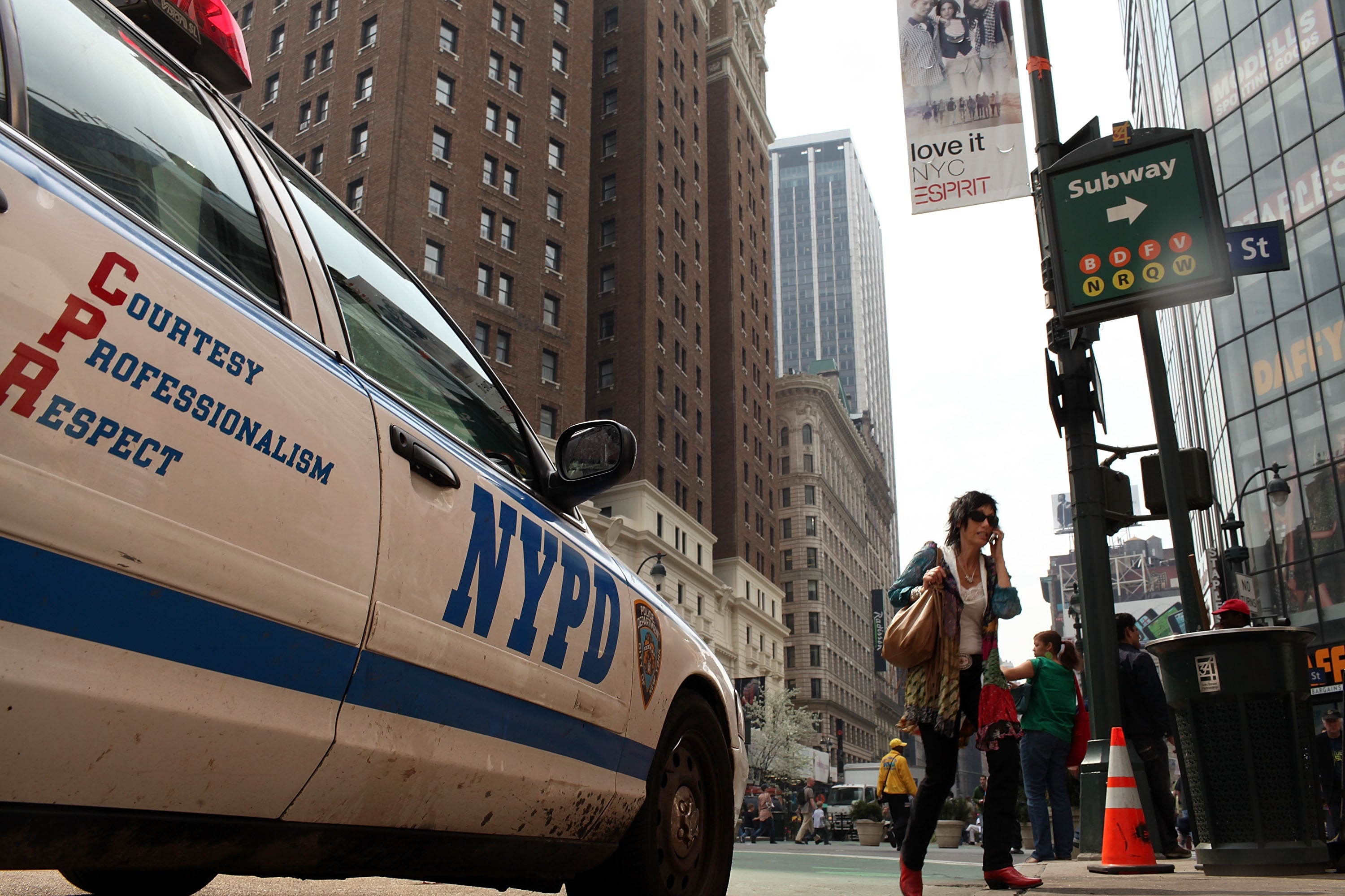 File: A woman walks by a New York City Police Department vehicle