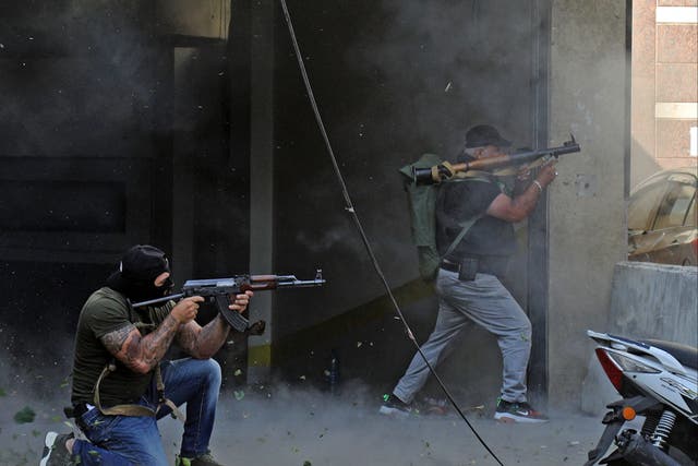 <p>Two members of Hezbollah exchange fire with snipers in Beirut yesterday </p>