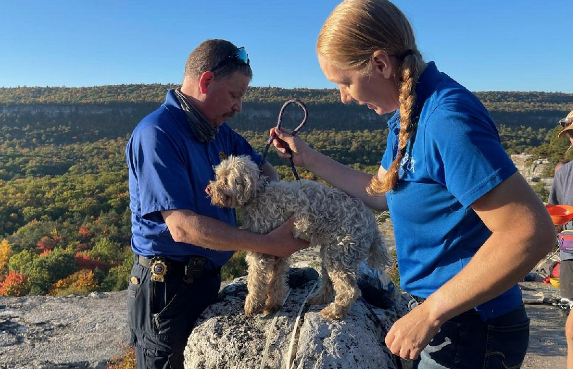 In this photo provided by New York State Parks on Wednesday, Oct. 13, 2021, Ulster County SPCA Executive Director Gina Carbonari, right, and SPCA Supervisor Chris West, left, check a rescued a 12-year-old dog named Liza, found trapped after five days deep inside the narrow, rocky crevice at Minnewaska State Park Preserve in Kerhonkson, N.Y.