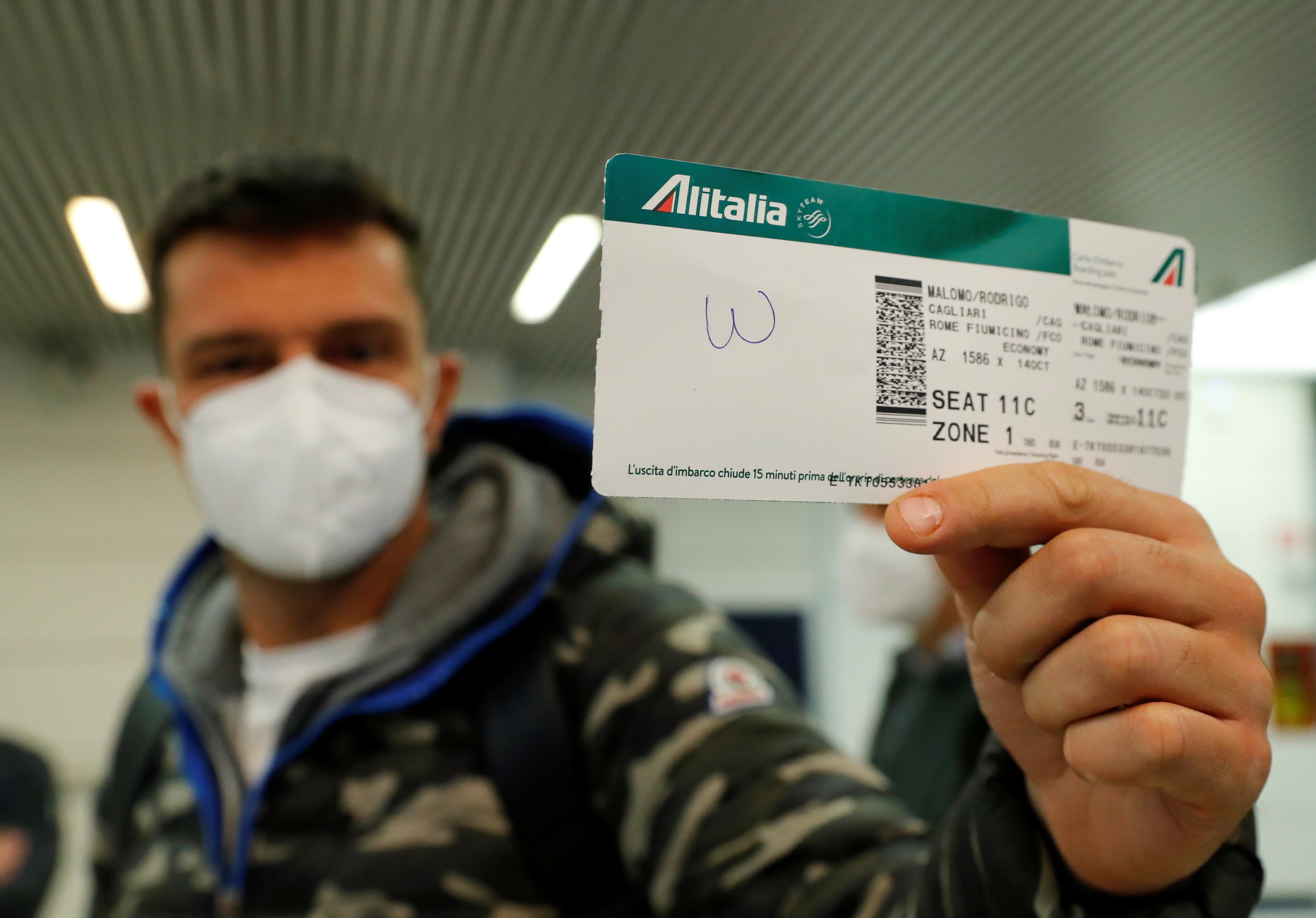 A passenger holds up a boarding pass from last ever Alitalia flight, AZ1586 from Cagliari to Rome