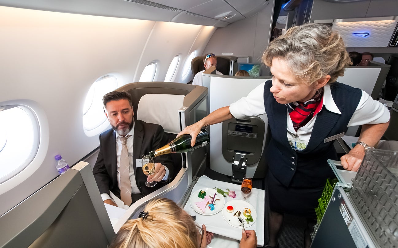 A member of cabin crew pours a glass of champagne in business class