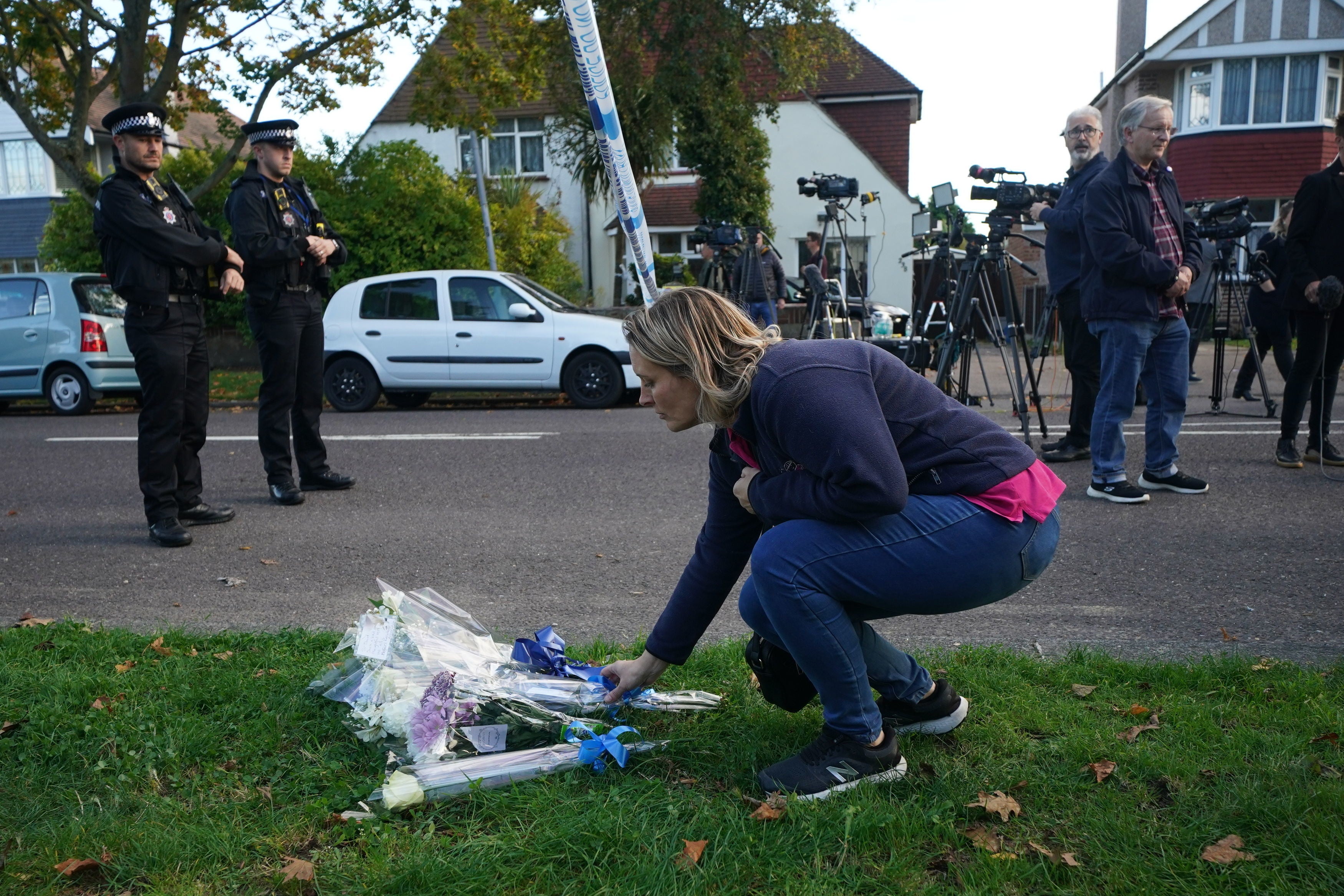 A mourner lays flowers at the scene near the Belfairs Methodist Church