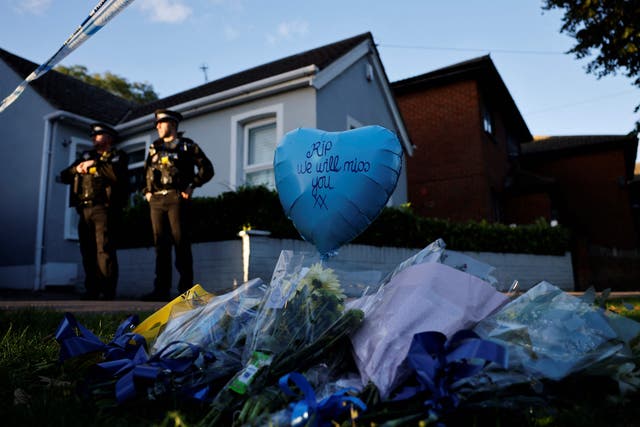 <p>Tributes are placed near the scene of Friday’s fatal stabbing incident as police oficers stand guard near the Belfairs Methodist Church in Leigh-on-Sea, Essex </p>