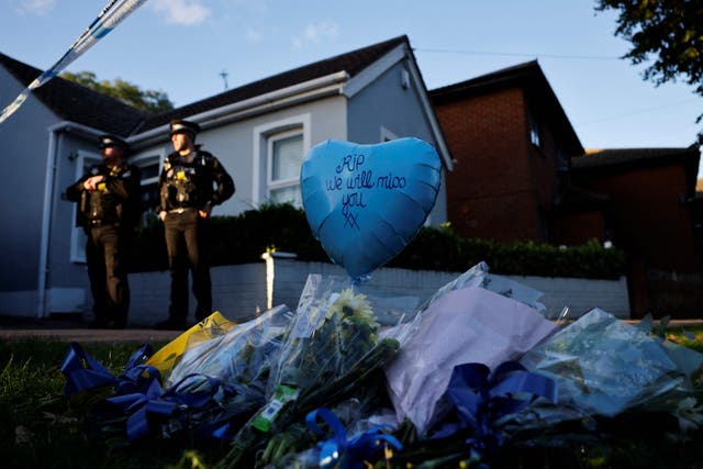 <p>Tributes are placed near the scene of Friday’s fatal stabbing incident as police oficers stand guard near the Belfairs Methodist Church in Leigh-on-Sea, Essex </p>