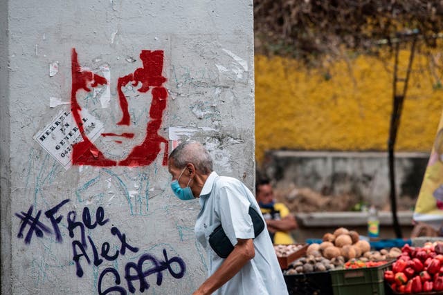 <p>A man walks past graffiti in Caracas demanding Colombian businessman Alex Saab’s freedom</p>