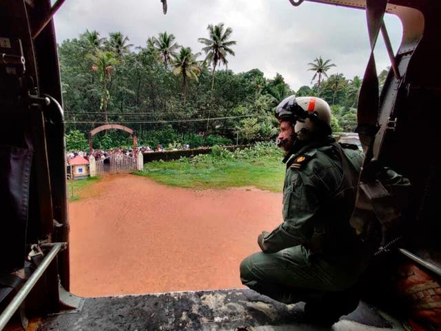 <p>A navy officer looks on from a helicopter during a mission to distribute relief material to people affected by heavy rain in Kerala’s Kottayam district </p>