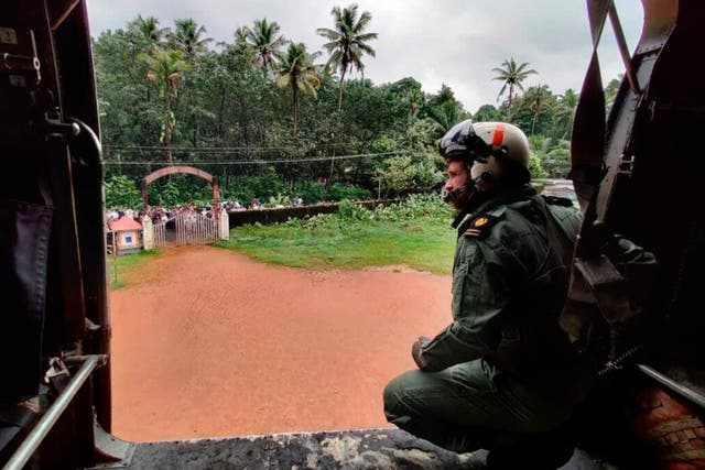 <p>A navy officer looks on from a helicopter during a mission to distribute relief material to people affected by heavy rain in Kerala’s Kottayam district </p>