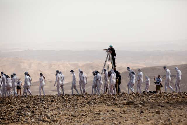 <p>Nude models pose for a photograph as American artist Spencer Tunick stands on a ladder to give instructions to them </p>