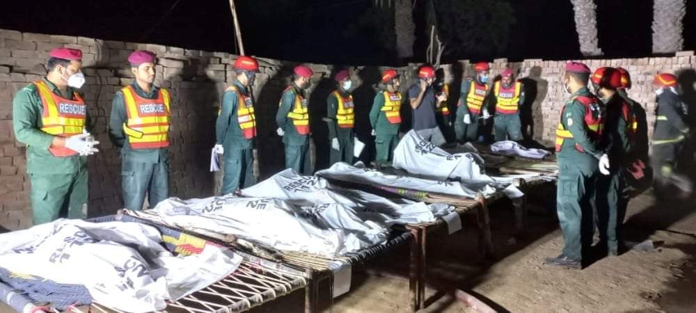Rescue workers gather near the bodies of the victims in Muzaffargarh, Pakistan