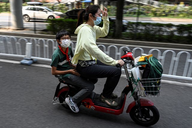 <p>File: A student leaves on a scooter following the end of the day’s school session in Beijing on 10 September 2021</p>